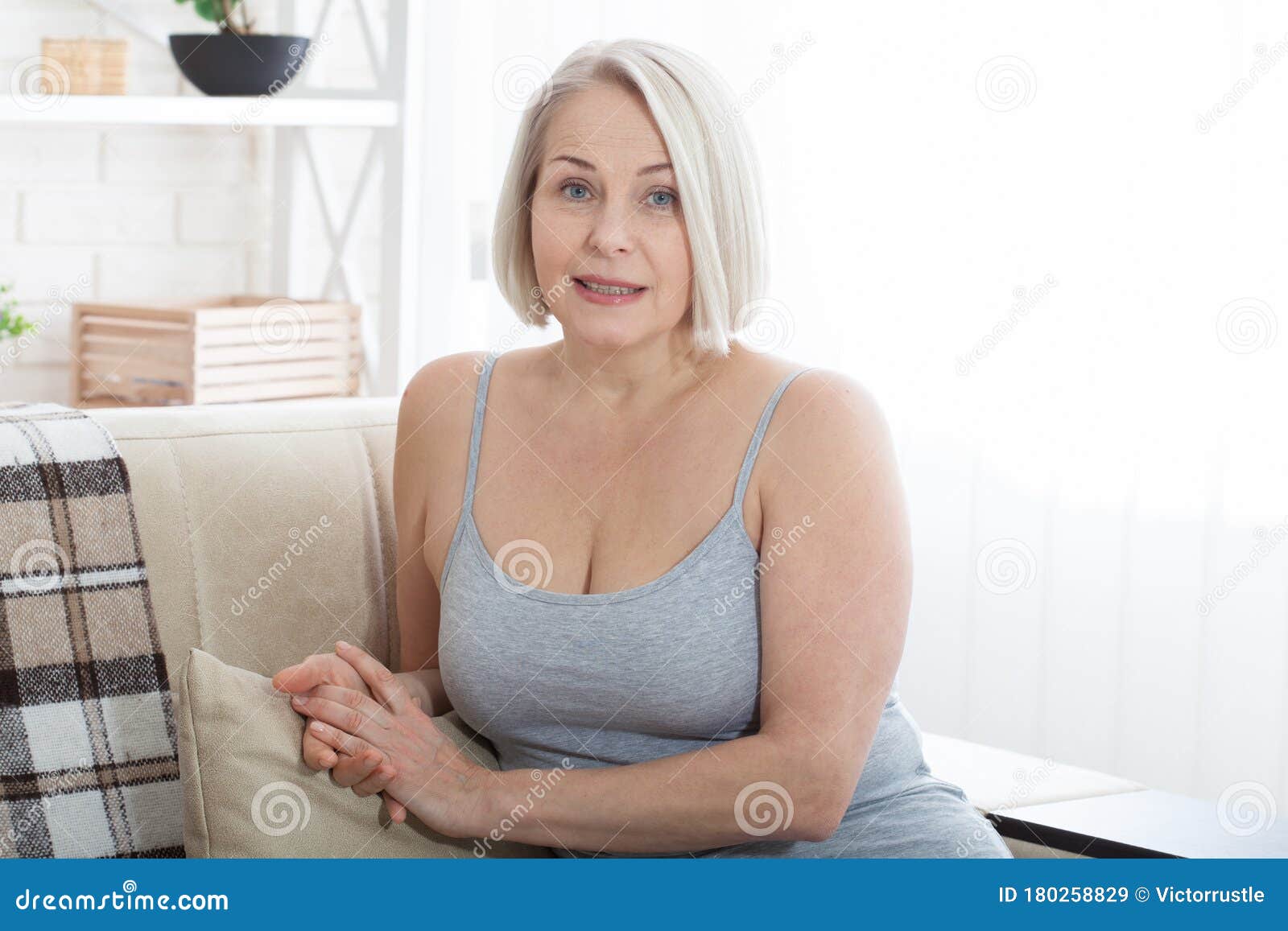 Active Beautiful Middle Aged Woman Smiling Friendly And Looking In Camera In Living Room Woman