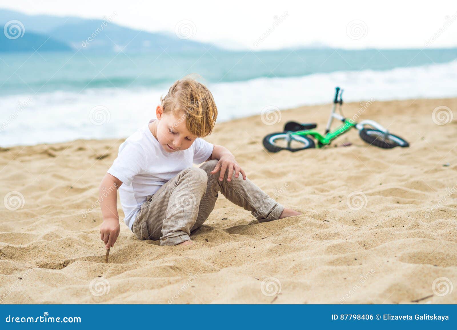 active blond kid boy and bicycle near the sea. toddler child dreaming and having fun on warm summer day. outdoors games for childr