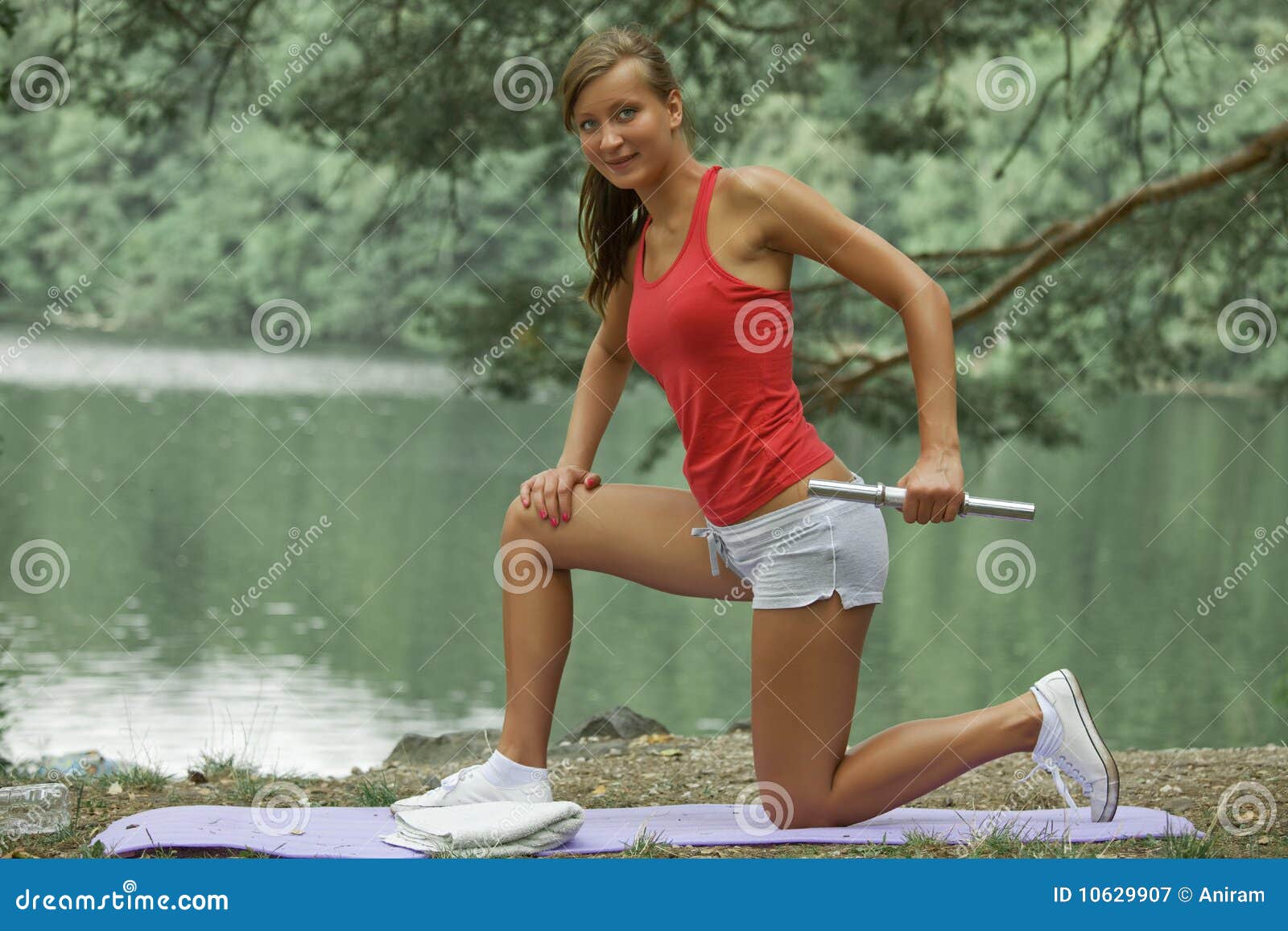 Active con pesa de gimnasia. Mujer feliz con pesa de gimnasia en la configuración al aire libre natural