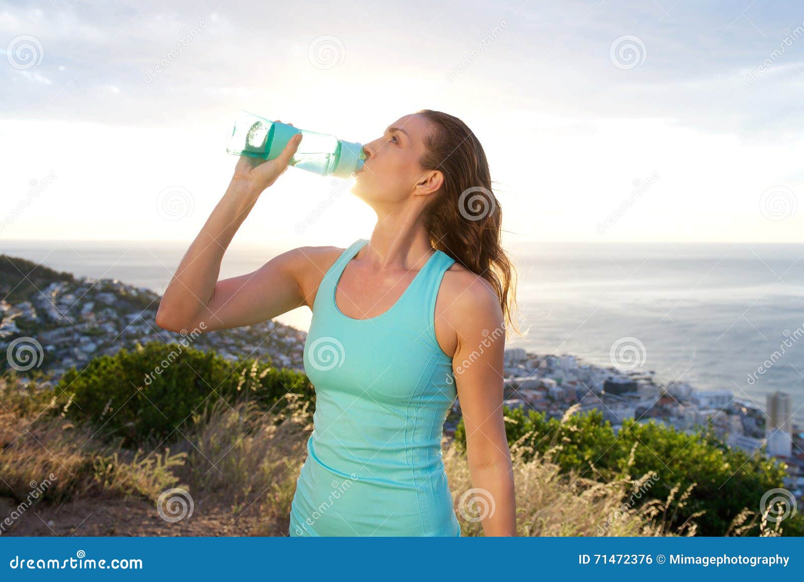 active woman drinking from water bottle in front of the sea