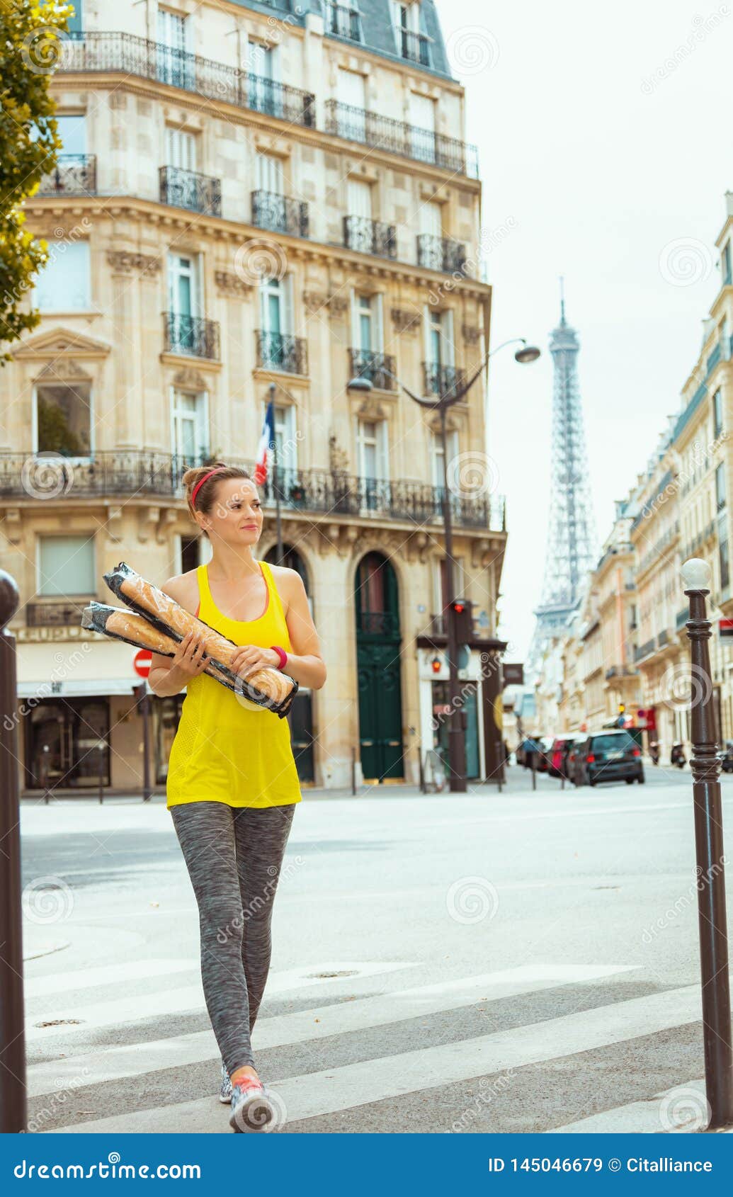 active woman with 2 french baguettes crossing street