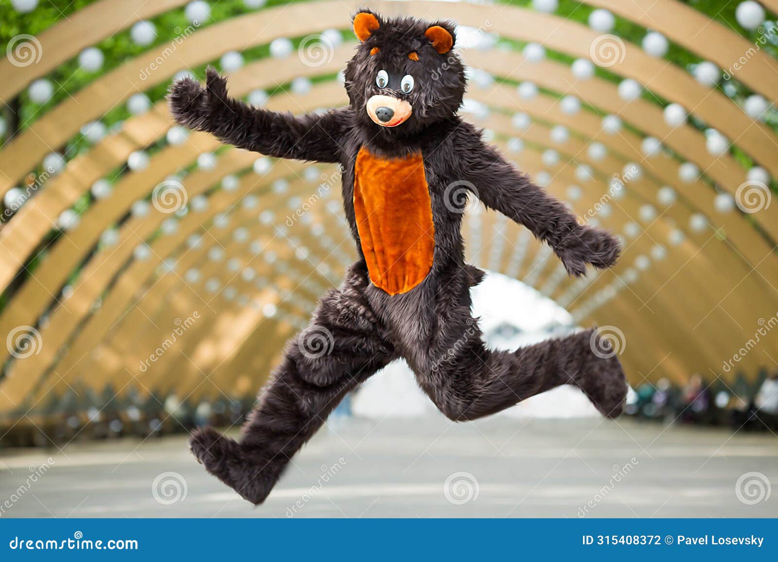 actor dressed as bear jumps under the arch of