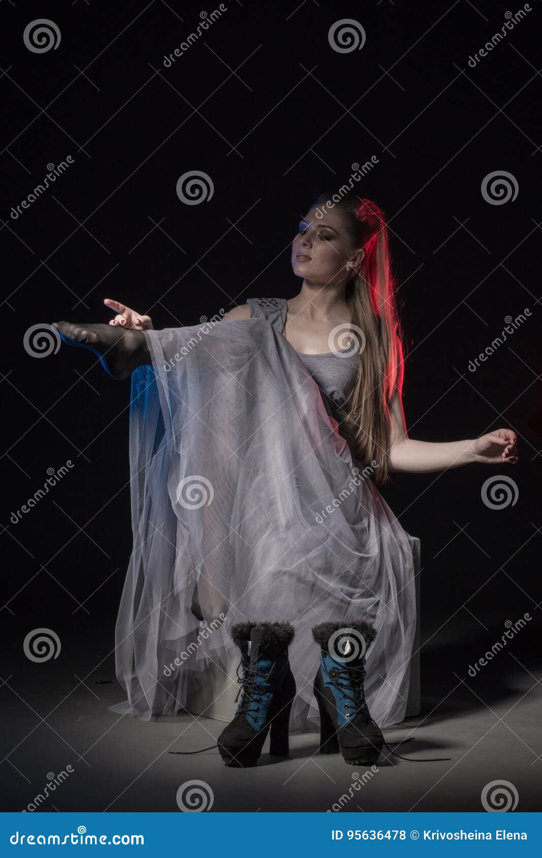 actress in a grey dress on a dark stage