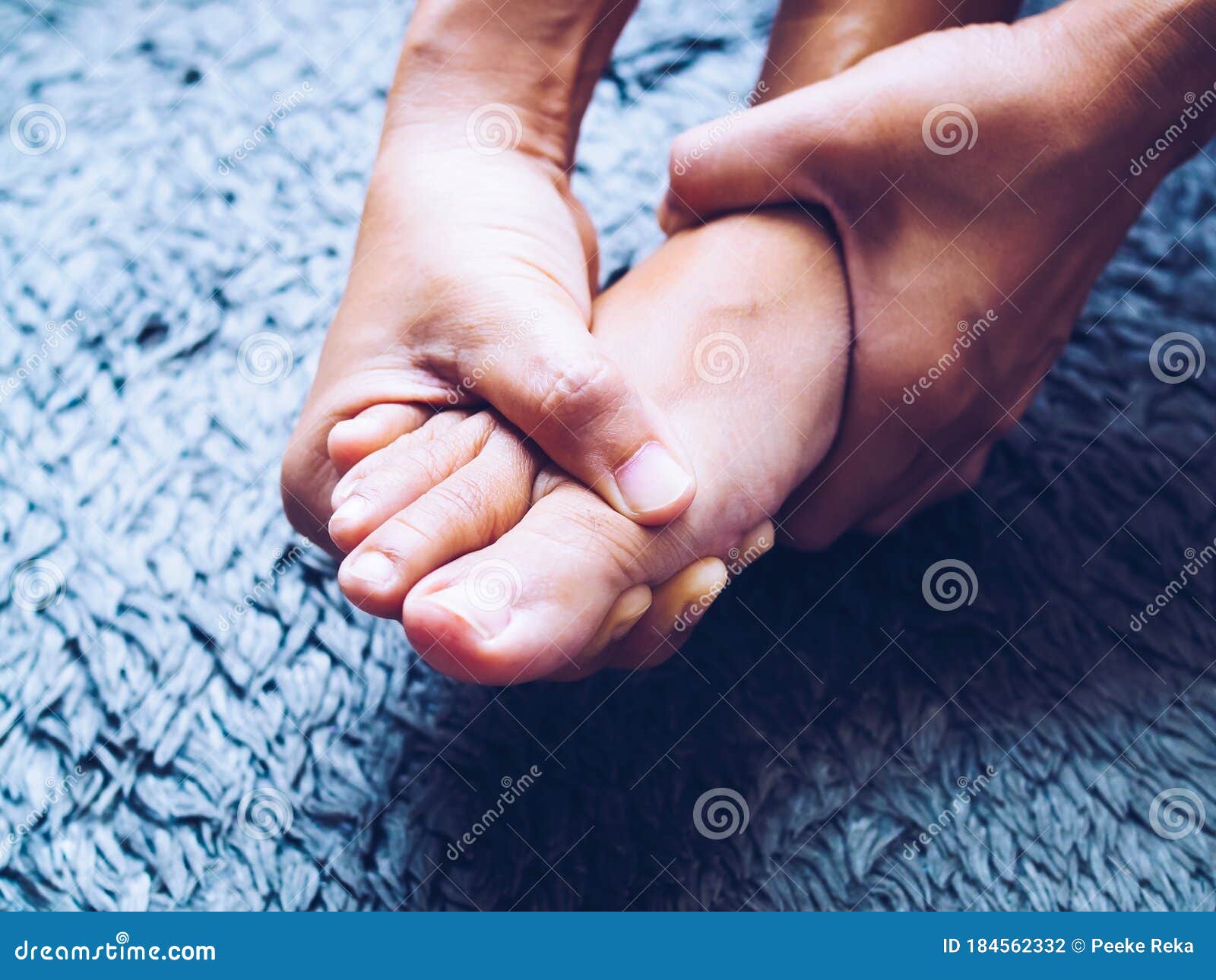 acute foot pain of thai asian women, using hand massage on feet to relieve severe sore feet. medical health care concept