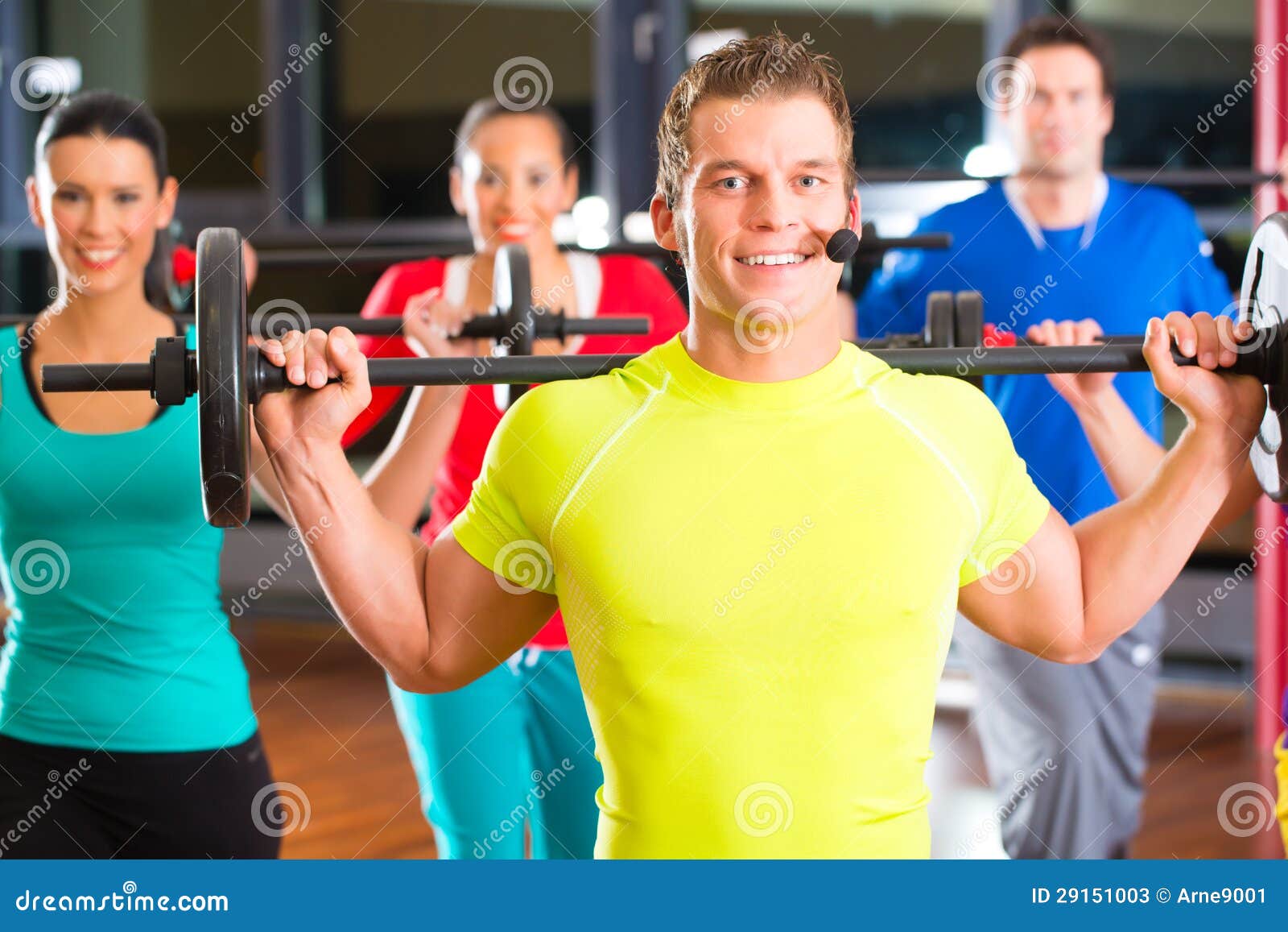 Addestramento del peso nella palestra con i dumbbells. Gruppo di giovani di sport che si preparano con il bilanciere ad una palestra per migliore forma fisica