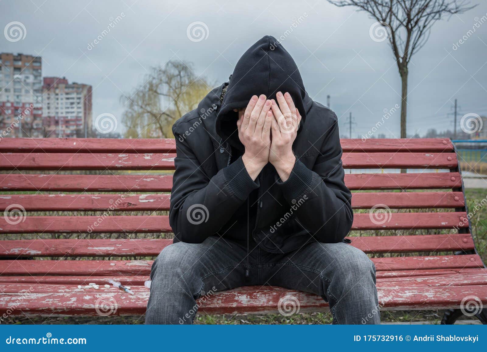 The Addict Sits Alone and Depressed on the Street, Covering His Face ...