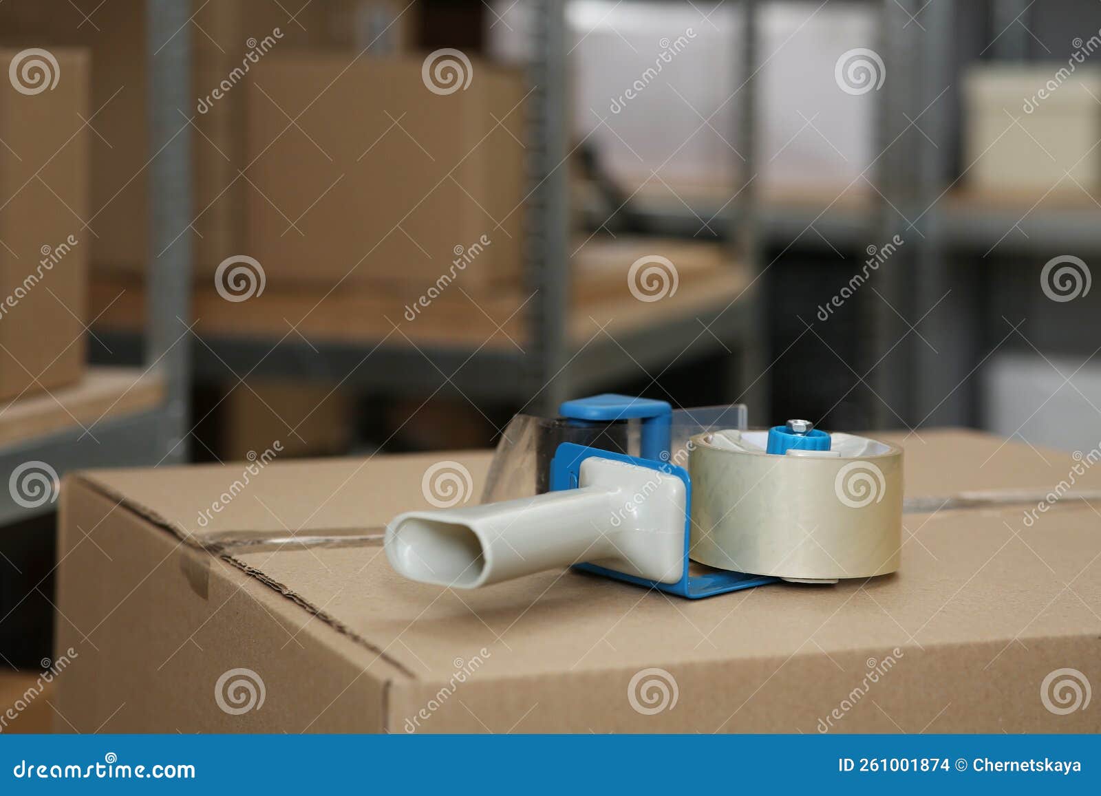 Adhesive Tape Dispenser on Cardboard Box Indoors. Space for Text Stock