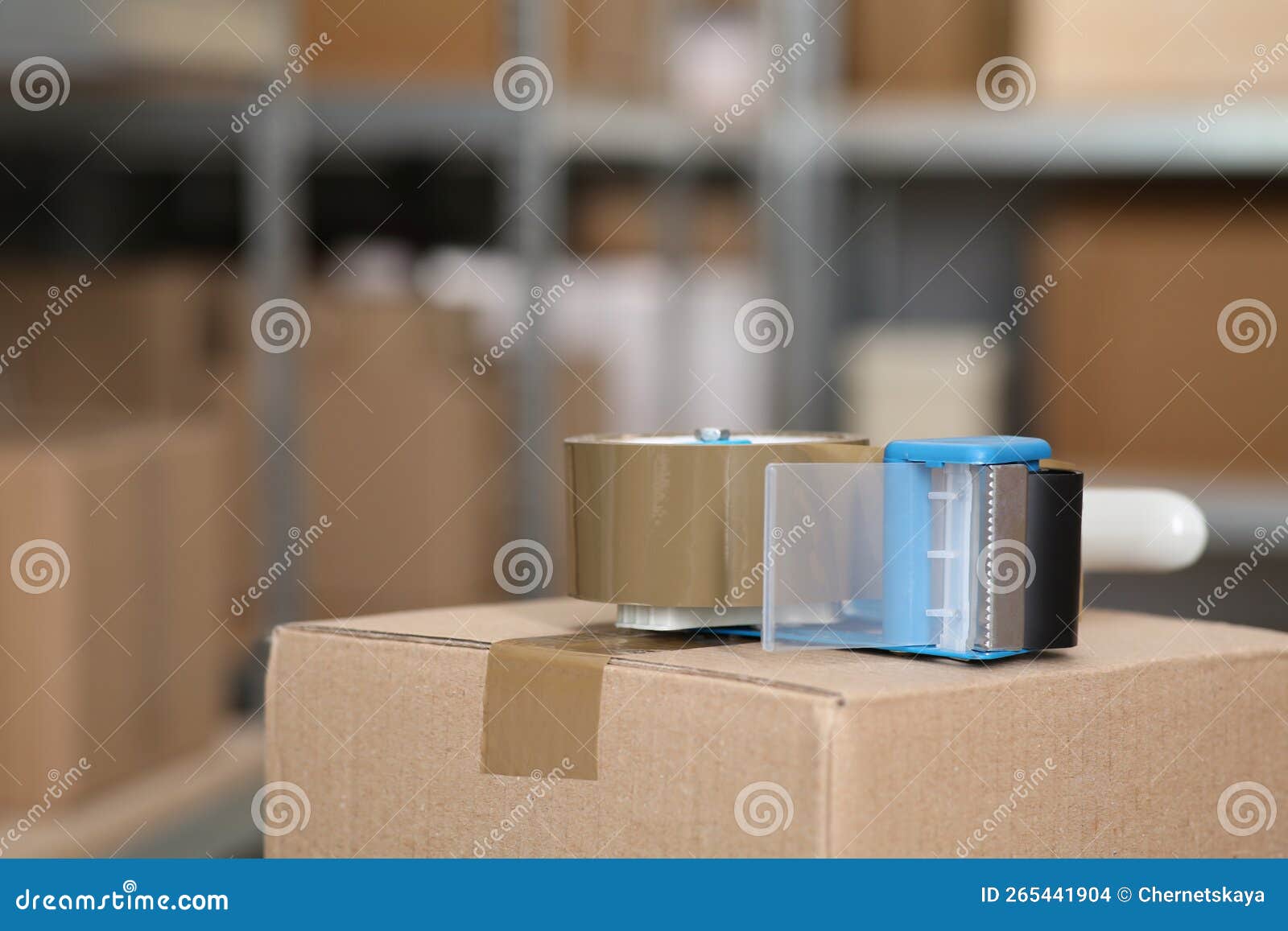 Adhesive Tape Dispenser on Cardboard Box Indoors. Space for Text Stock