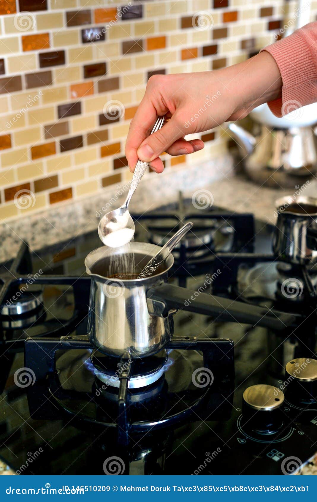 Adding sugar into the coffee pot on the oven preparing turkish coffee