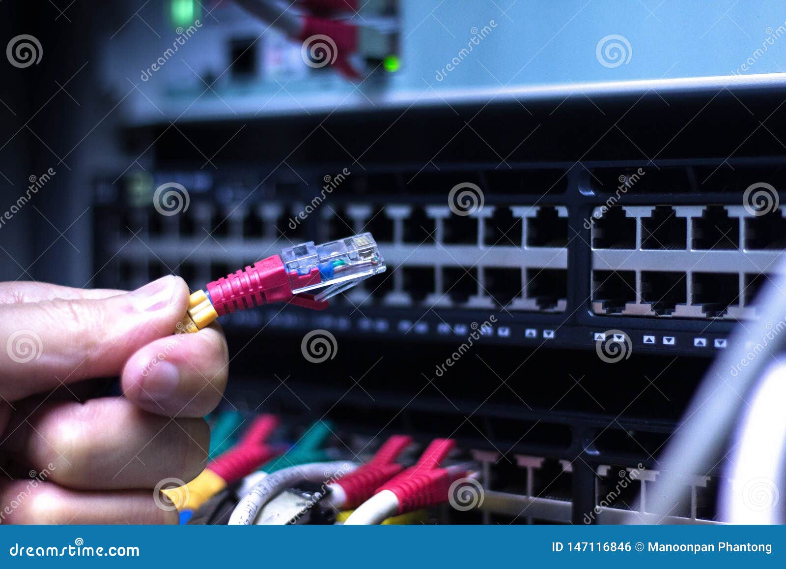 administrator hand with network cables connected to servers in datacenter