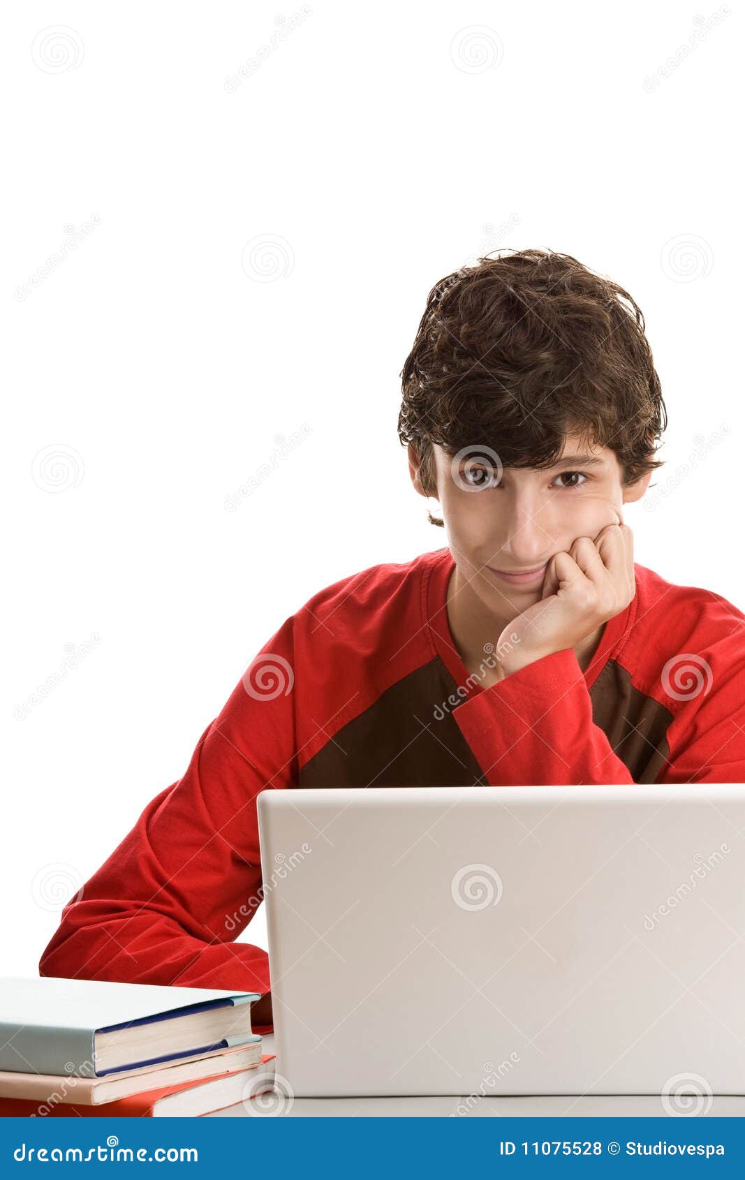 Adolescente dietro lo scrittorio con il computer portatile. Adolescente che si siede dietro lo scrittorio con il computer portatile isolato sulla priorità bassa bianca