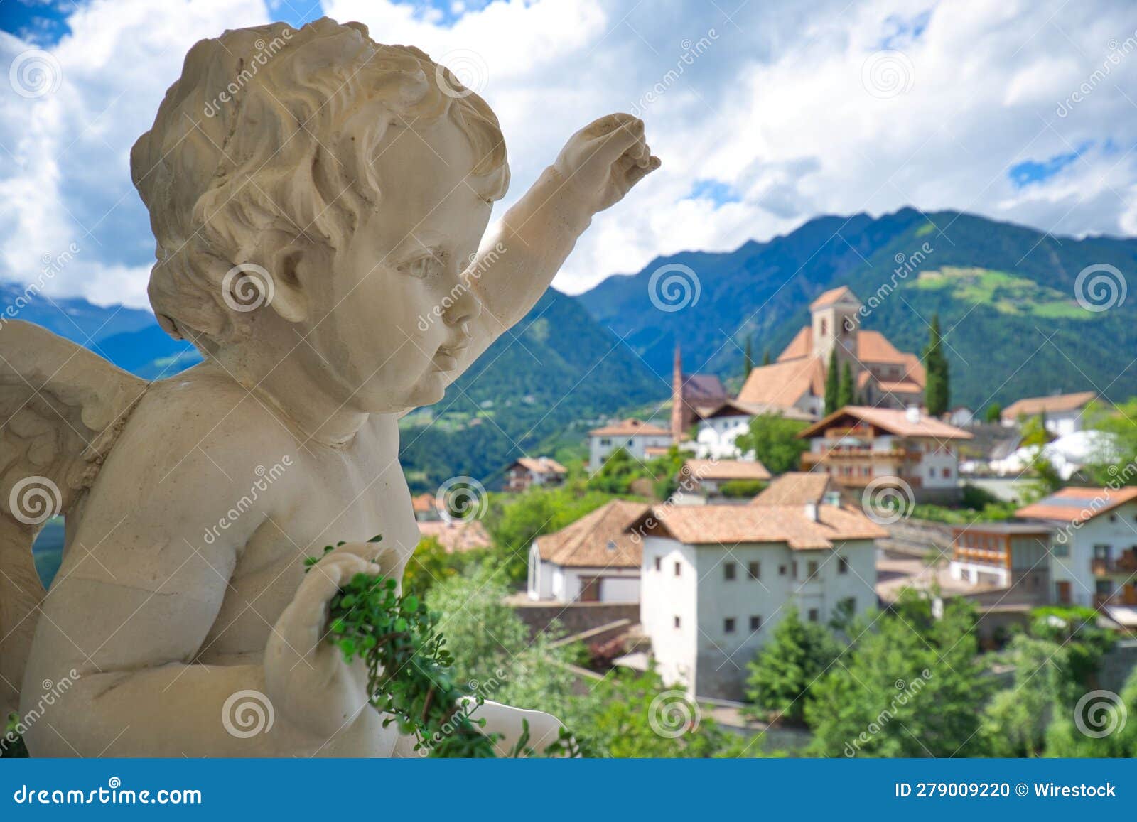 adorable angel sculpture on a rooftop overlooking the cityscape in scena, south tyrol, italy