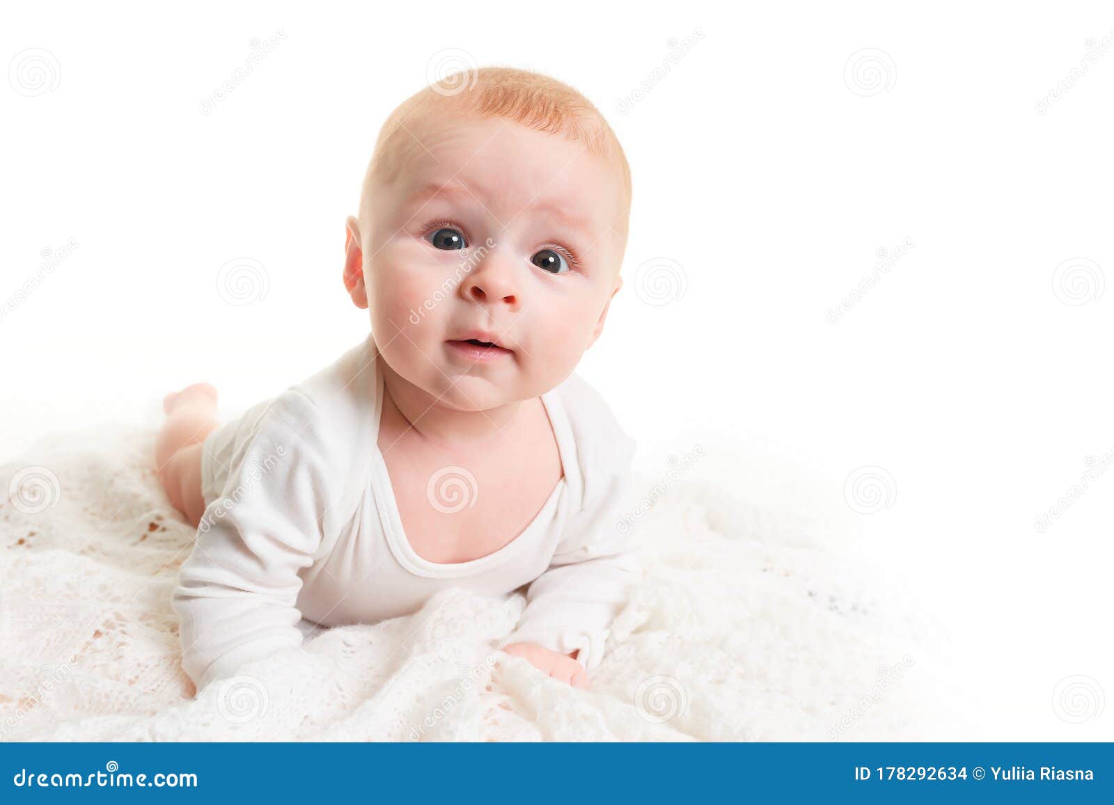 A Small 4 Month Old Baby Lies on a Soft Light Blanket and Looks at the ...