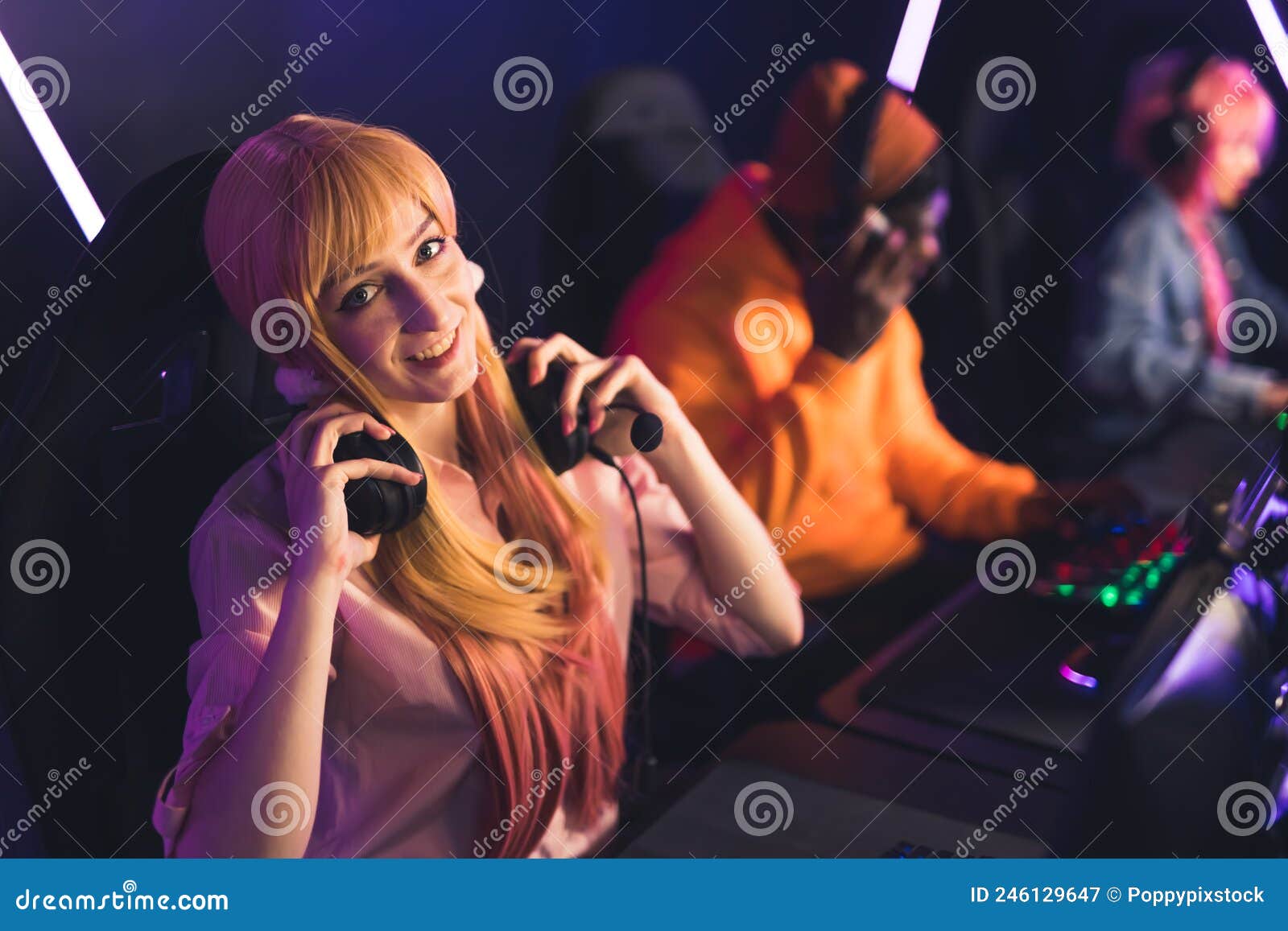 Adorable Caucasian Long Haired Blonde Gamer Girl Looking At Camera Smiling And Putting Her 