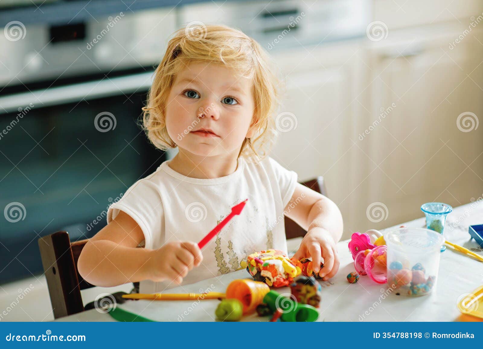 adorable cute little toddler girl with colorful clay at home. healthy baby playing and creating toys from play dough at