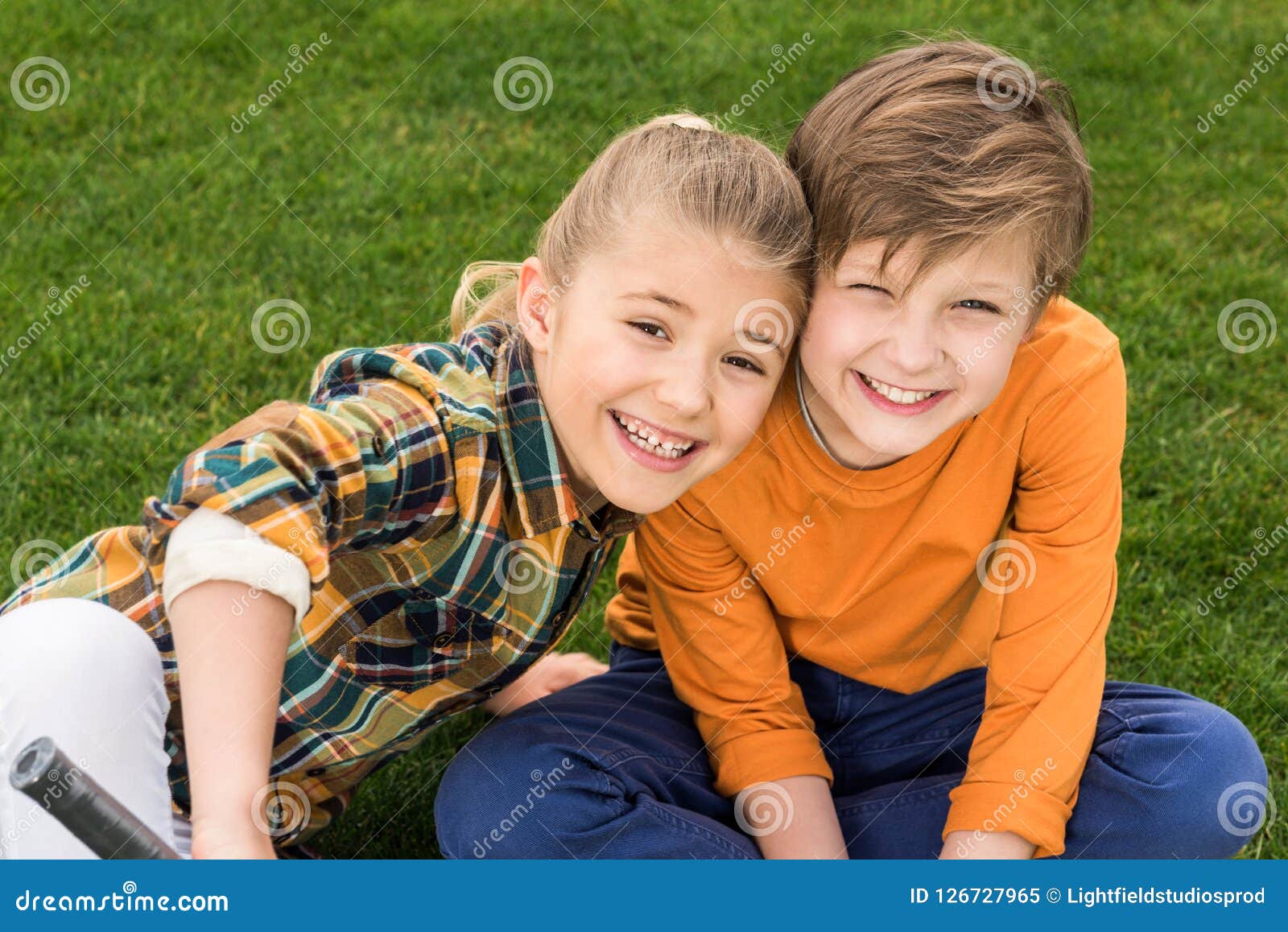 Adorable Happy Brother and Sister Sitting Together on Green Grass and ...
