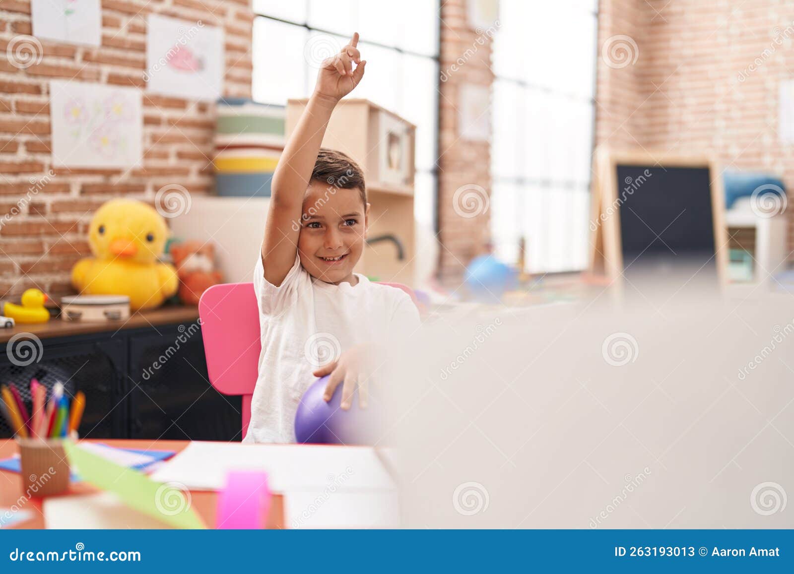 Adorable Hispanic Toddler Sitting on Table Having Lesson at