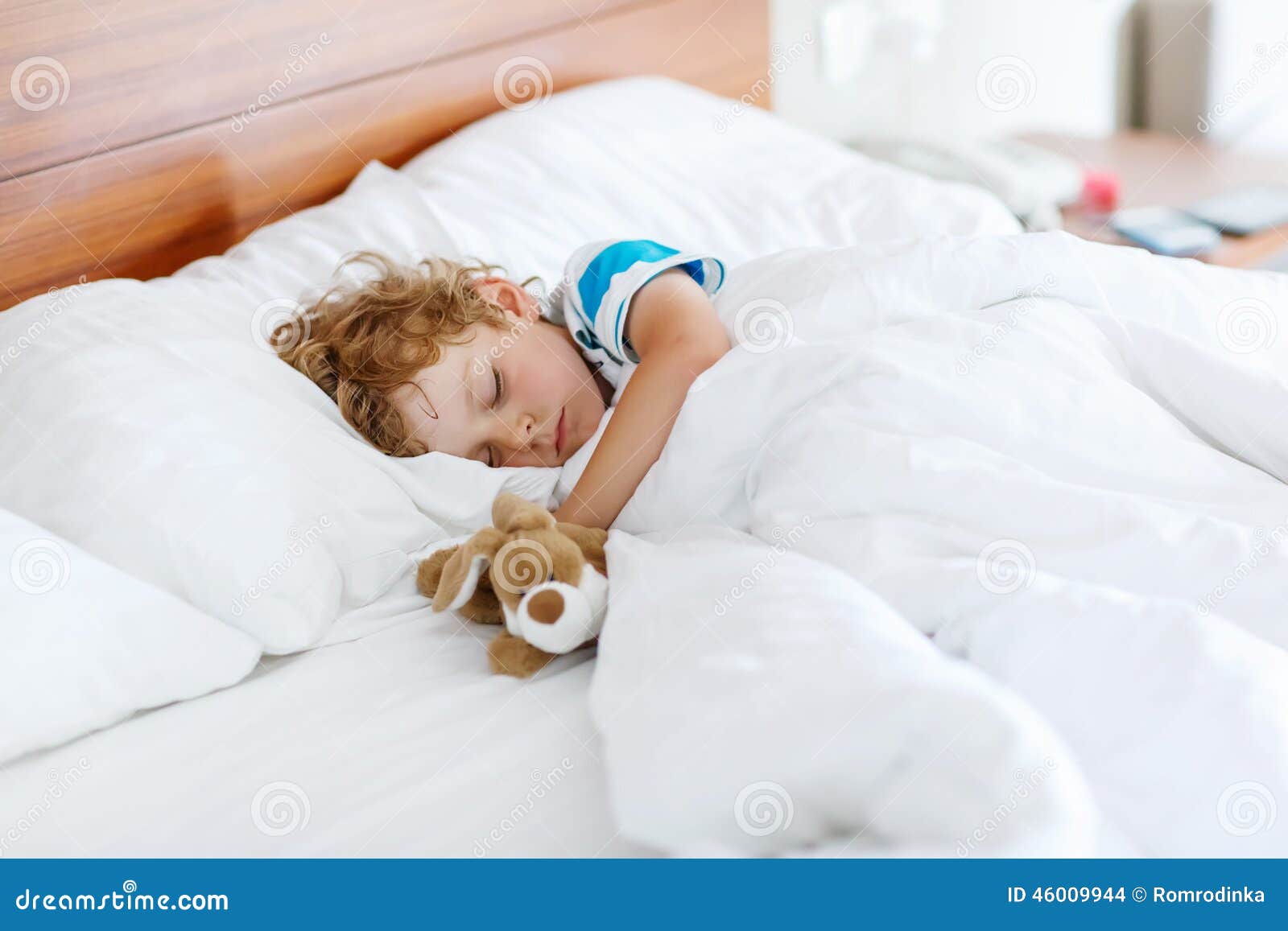 Adorable Kid Boy Sleeping and Dreaming in His White Bed with Toy Stock