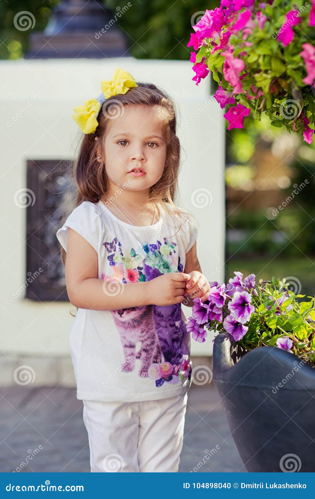 adorable little baby girl with pout tiny lips and brunette hairs posing in central park wearing stylish white colourful clothes a