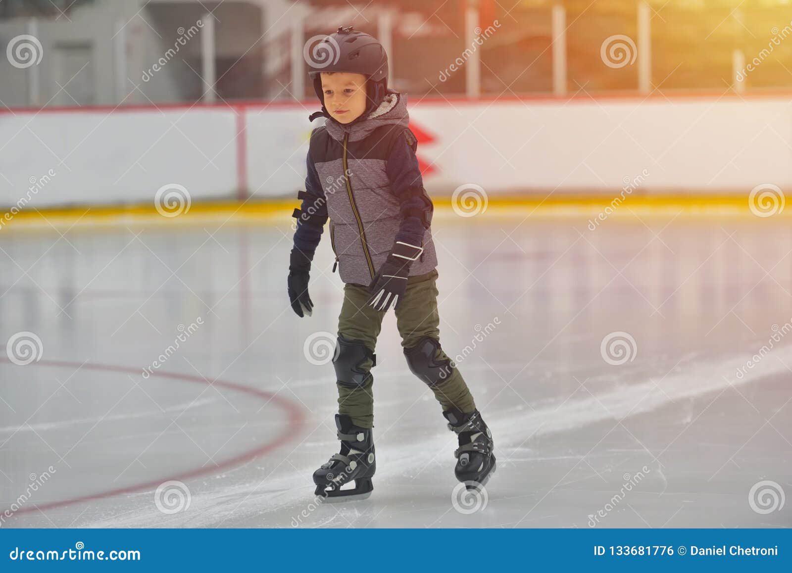 adorable little boy in winter clothes with protections skating o