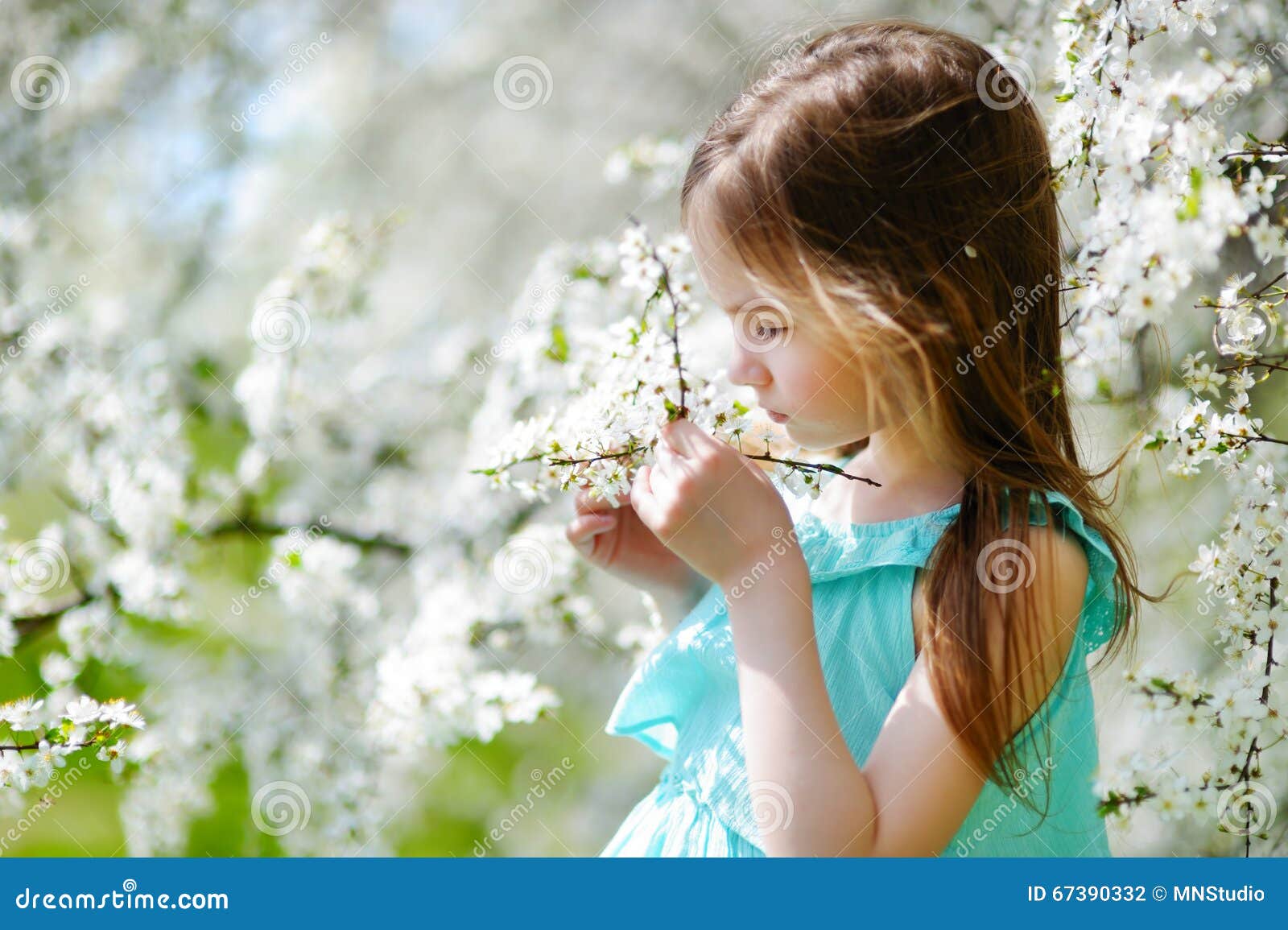 Adorable little girl in blooming cherry garden on beautiful spring day