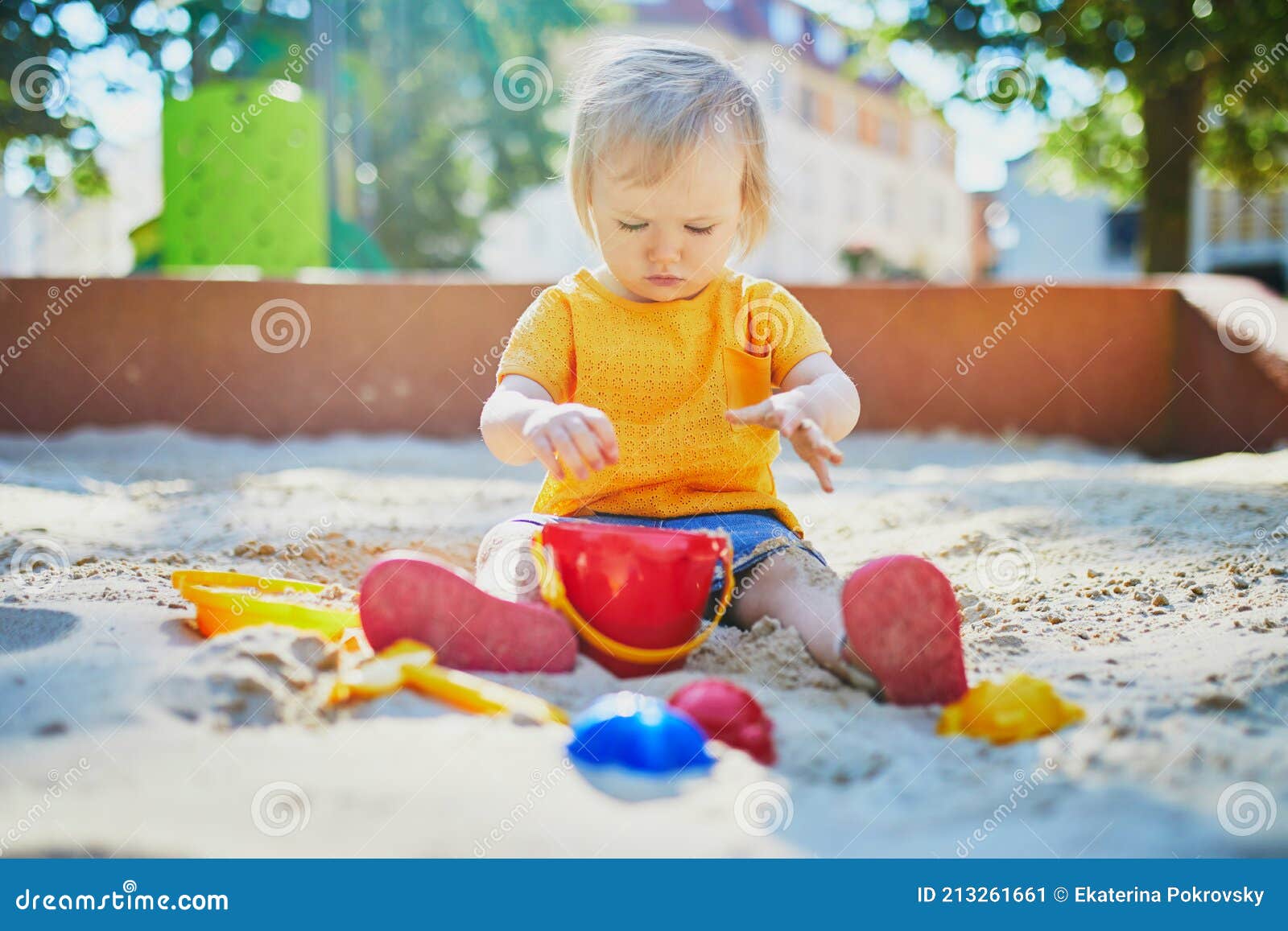 adorable little girl having fun on playground in sandpit