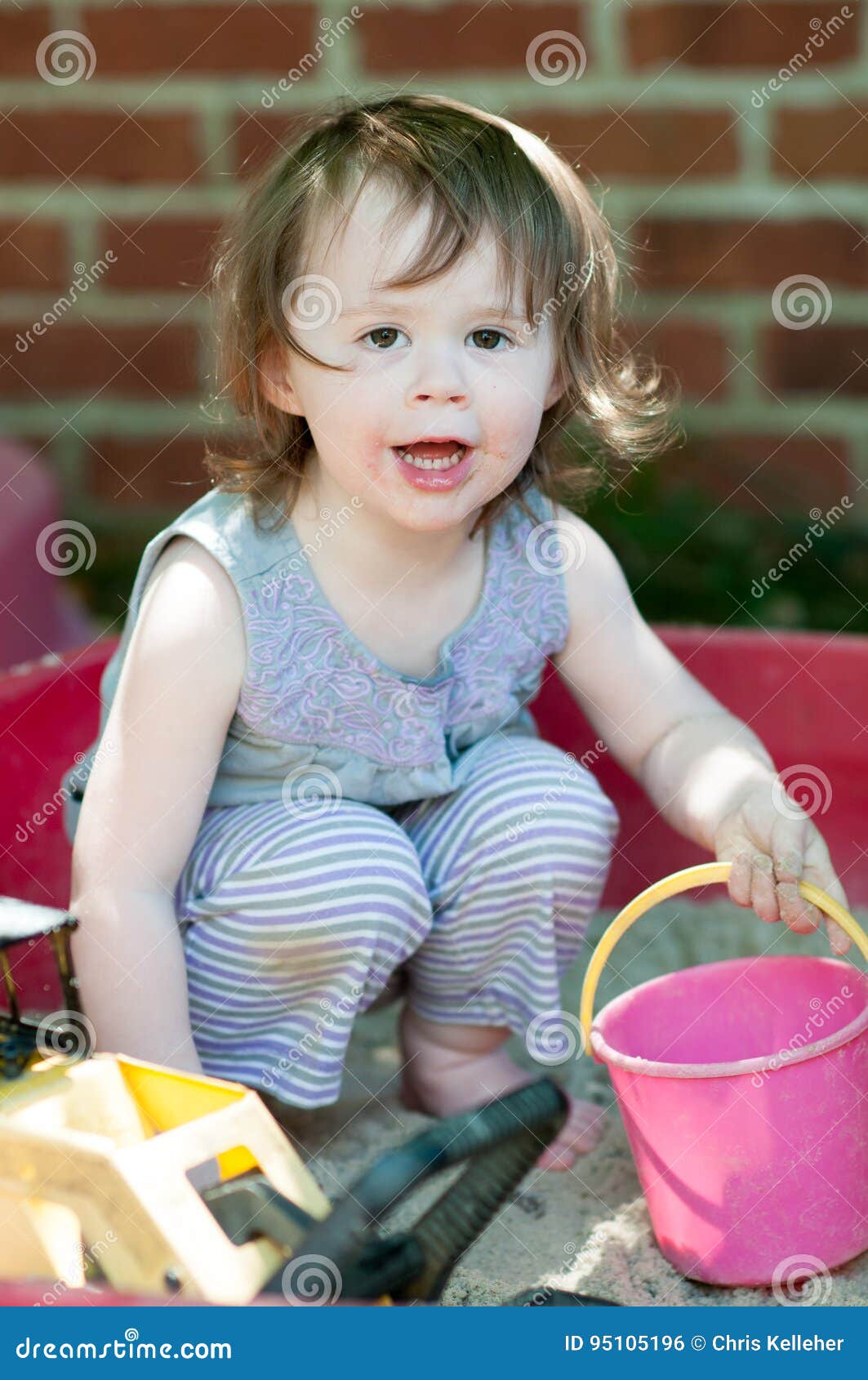 An adorable little girl playing in a sandbox