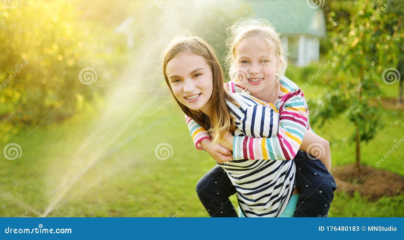 Adorable Little Girl Playing With A Sprinkler In A 