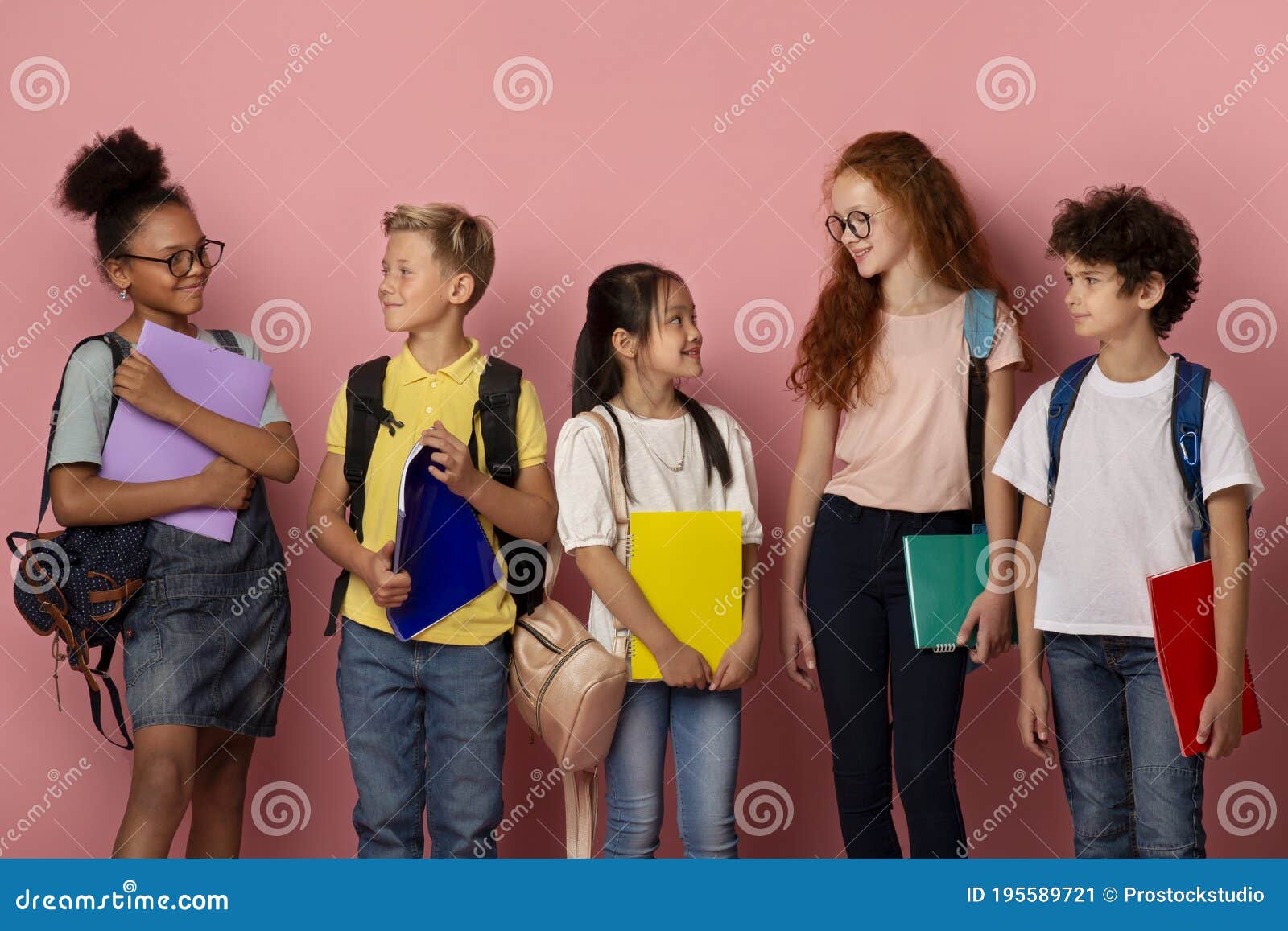 adorable schoolkids of different races and ages looking at each other over pick background