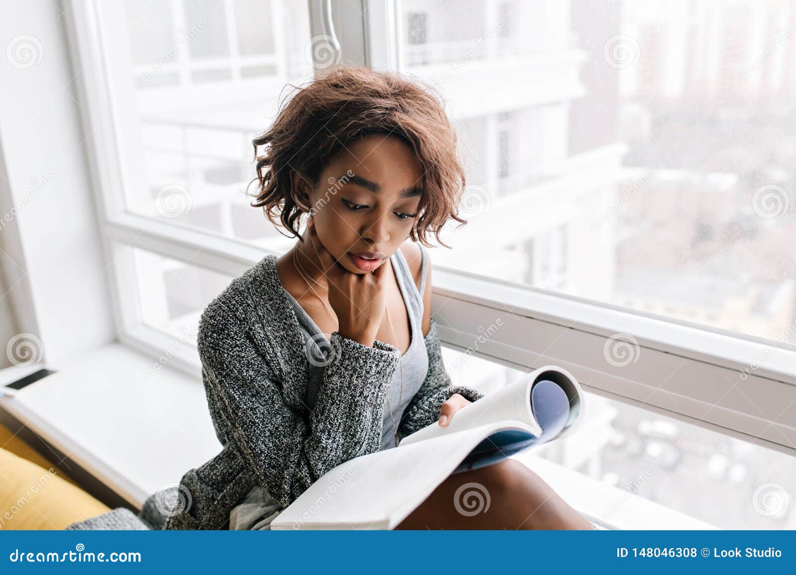 Adorable Young Girl With Short Curly Hair Absorbedly Reading