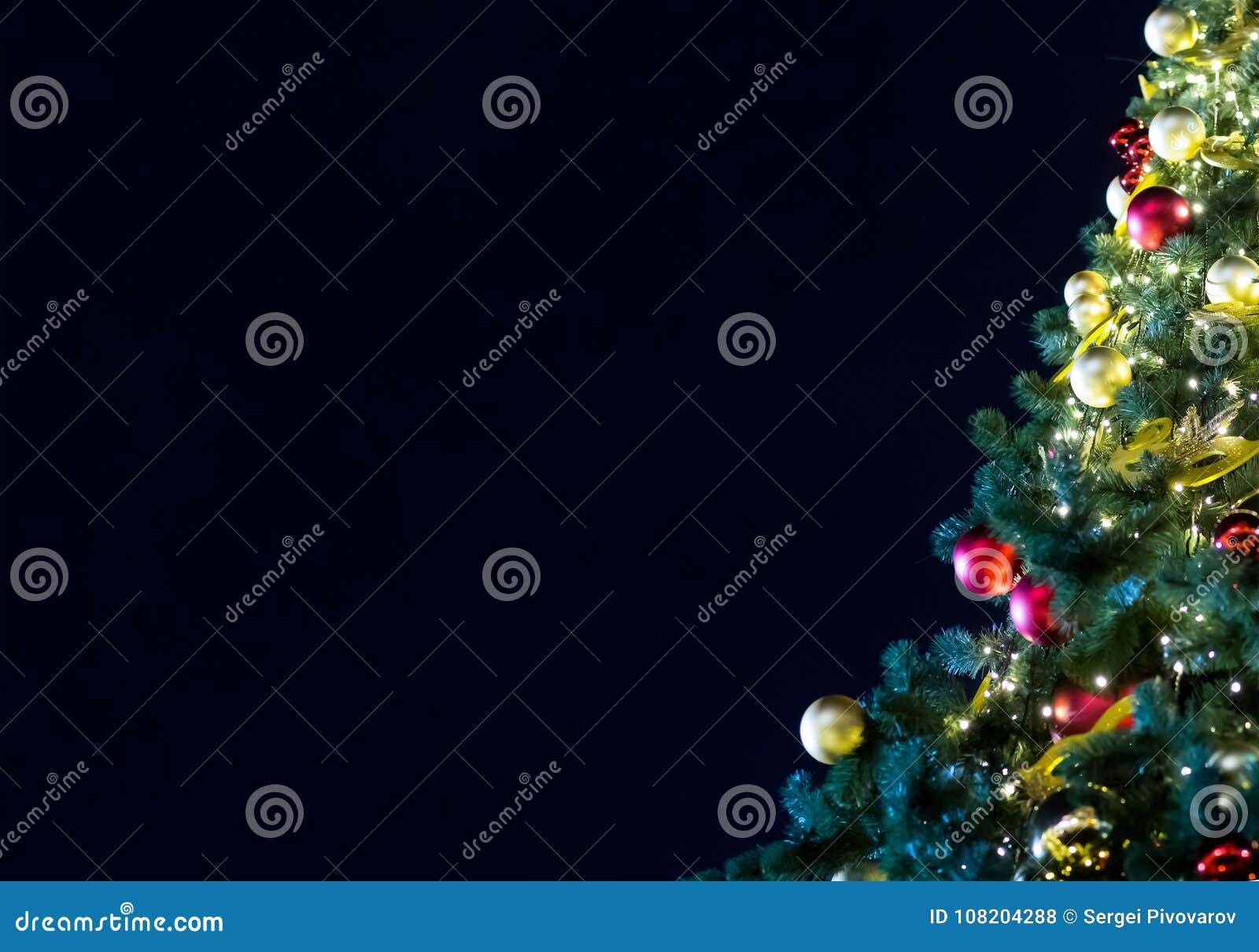 Adornado con el árbol festivo del árbol de navidad rojo de oro de las bolas en un fondo de un cielo nocturno oscuro con el espacio de la copia, la fundación es una invitación de la tarjeta de felicitación