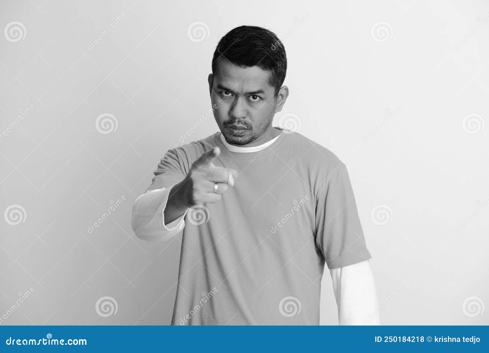 adult asian man looking to camera with angry expression while pointing finger forward