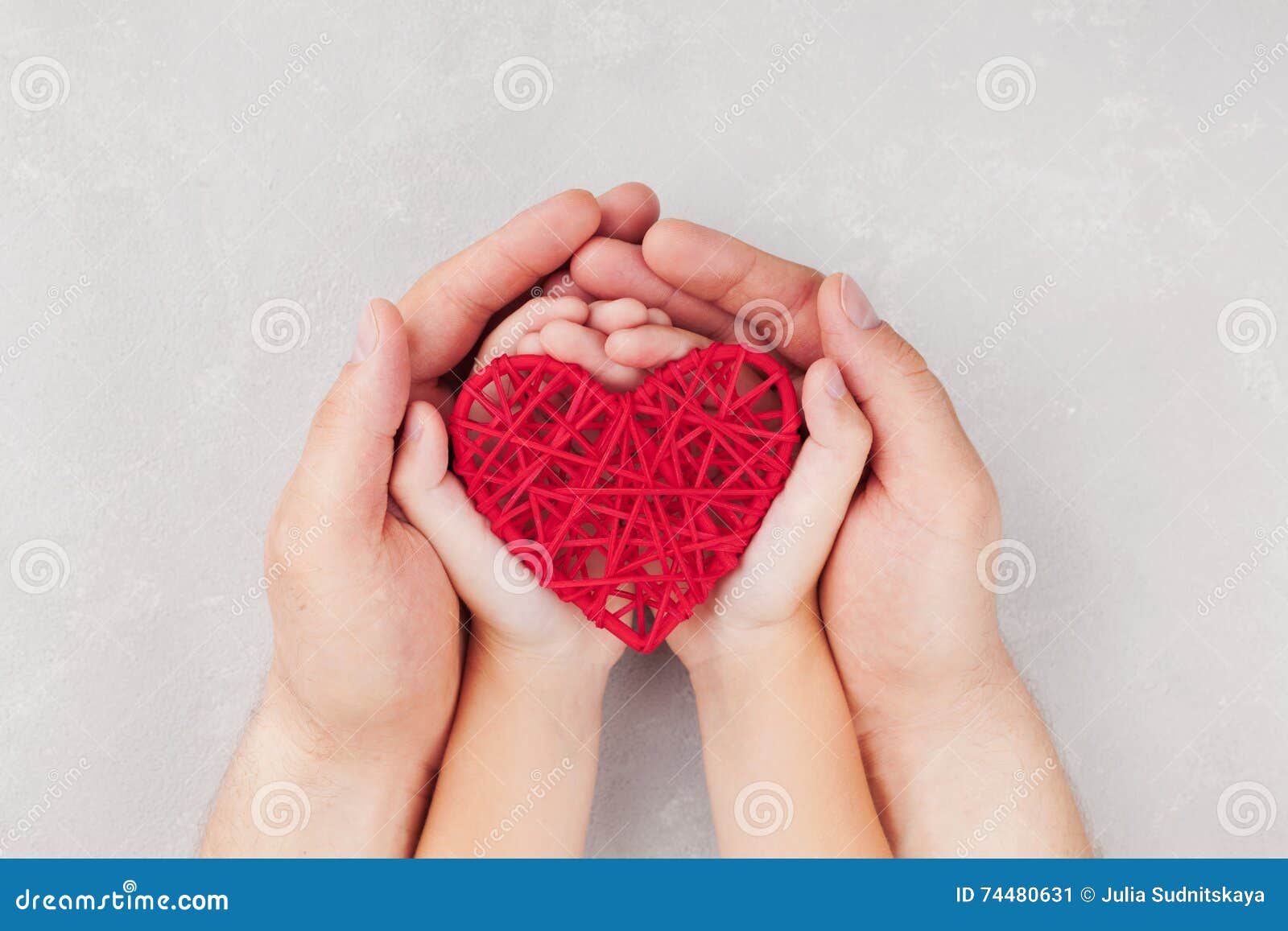 adult and child holding red heart in hands top view. family relationships, health care, pediatric cardiology concept.