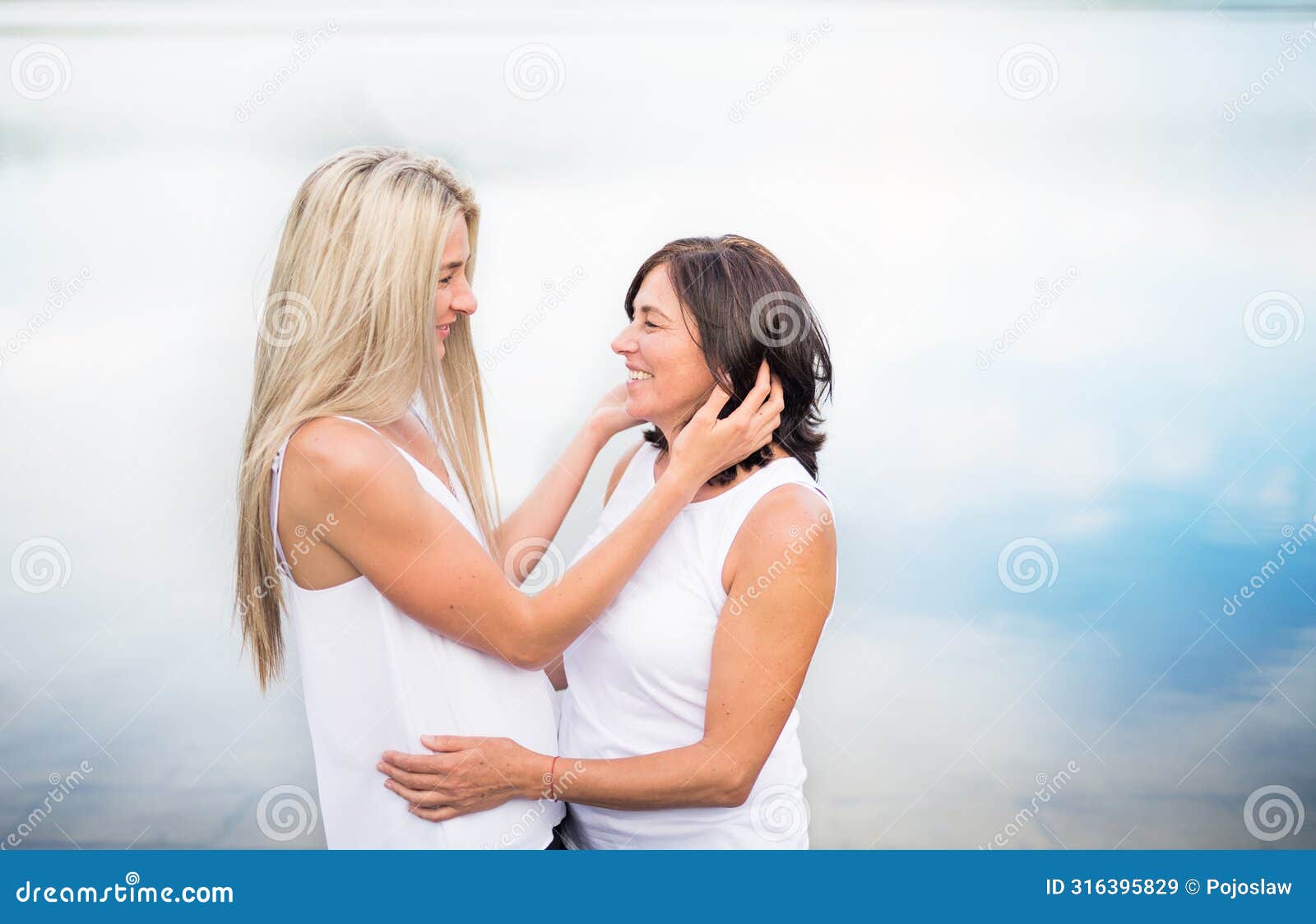adult daughter spending time with her mother outdoors. beautiful daughter holding each other lovingly, hugging