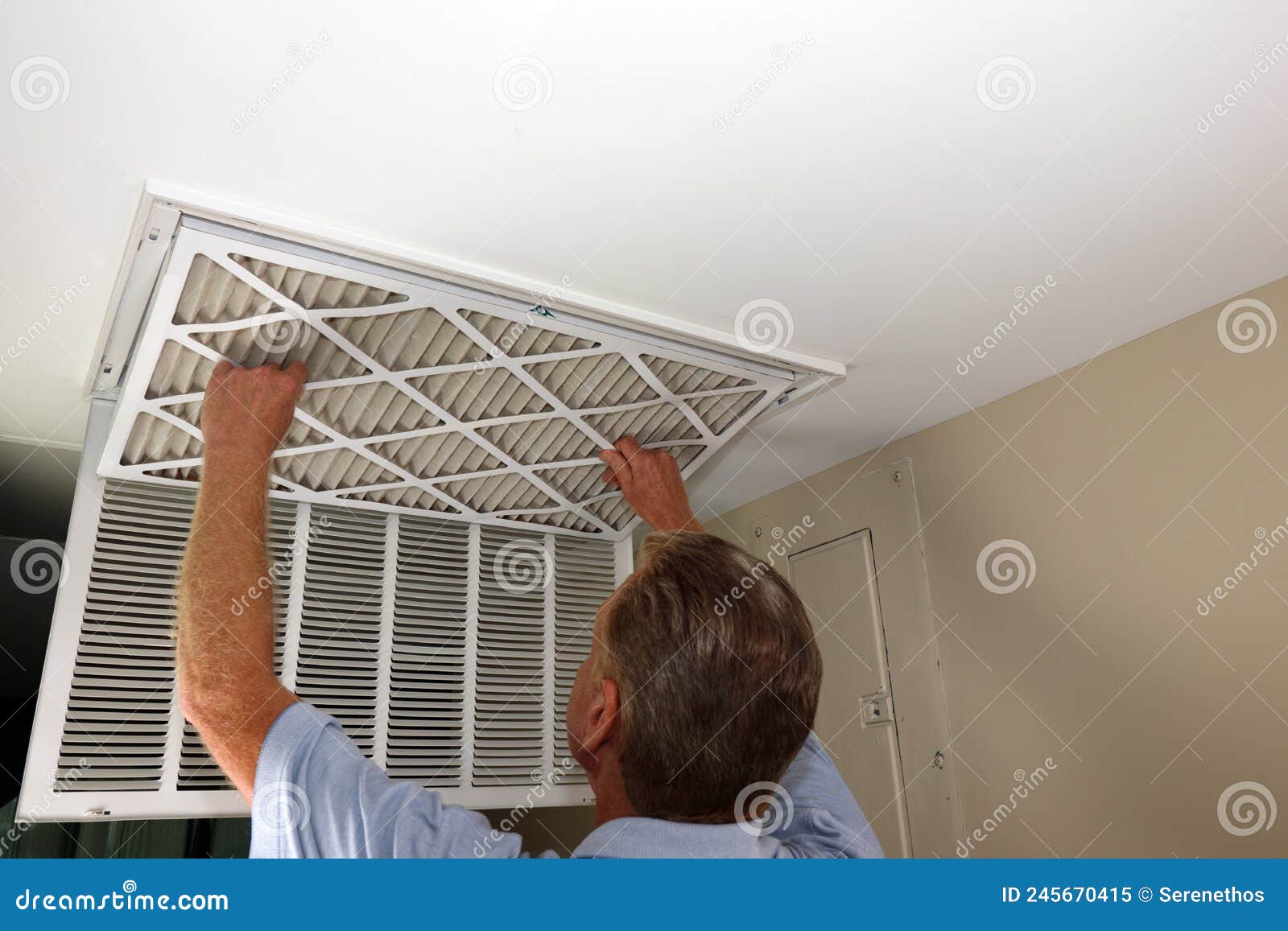 adult male removing air filter from a home furnace ceiling vent
