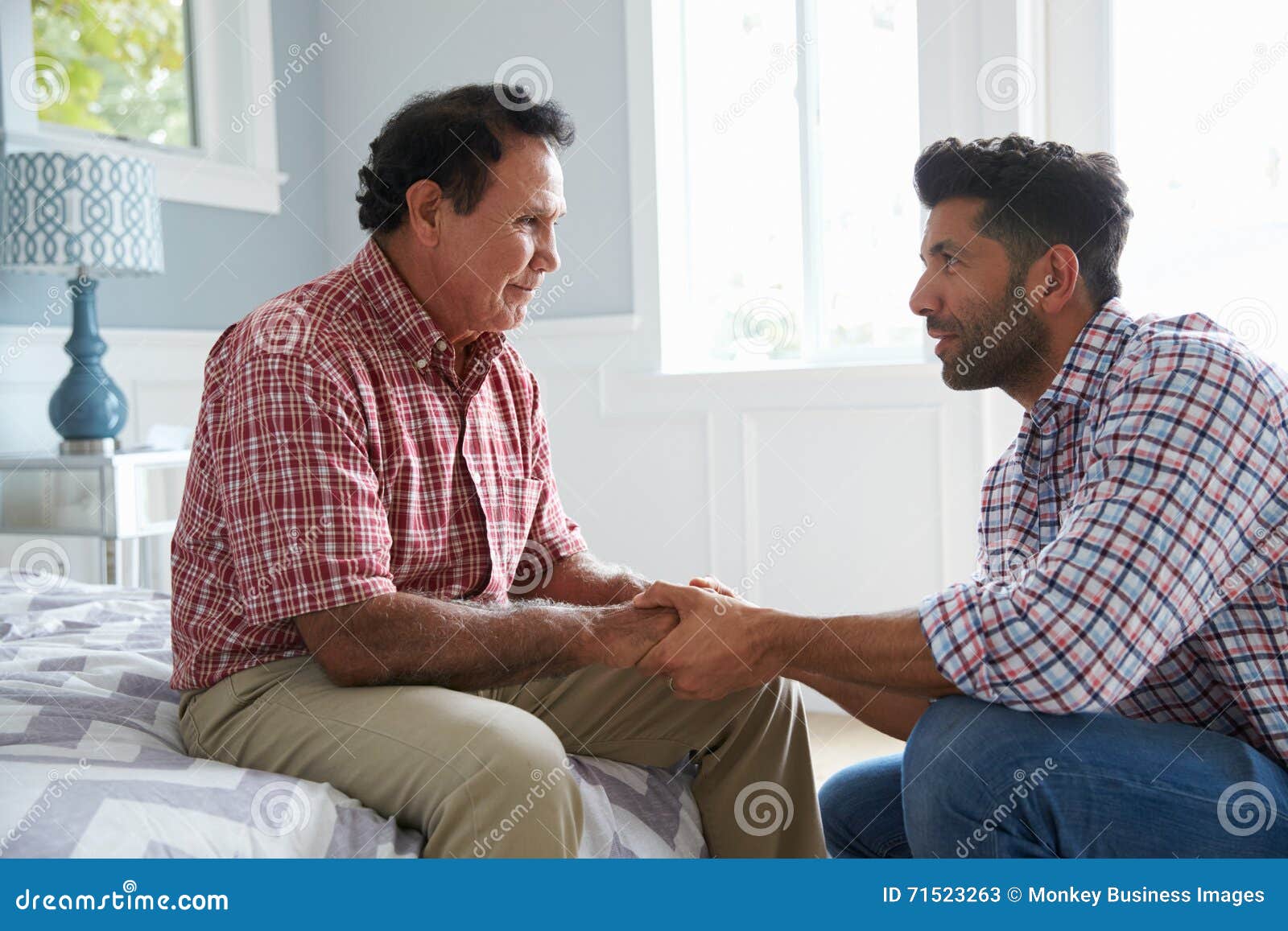 adult son comforting father suffering with dementia