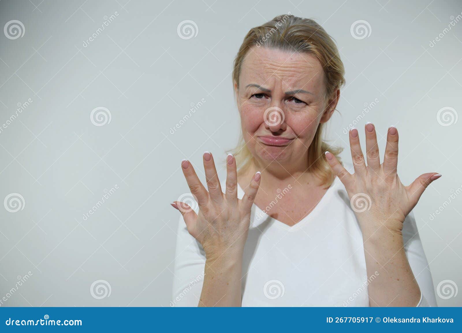 adult woman is offended upset like child she put out fingers with fan of both hands looks into frame completely frowning