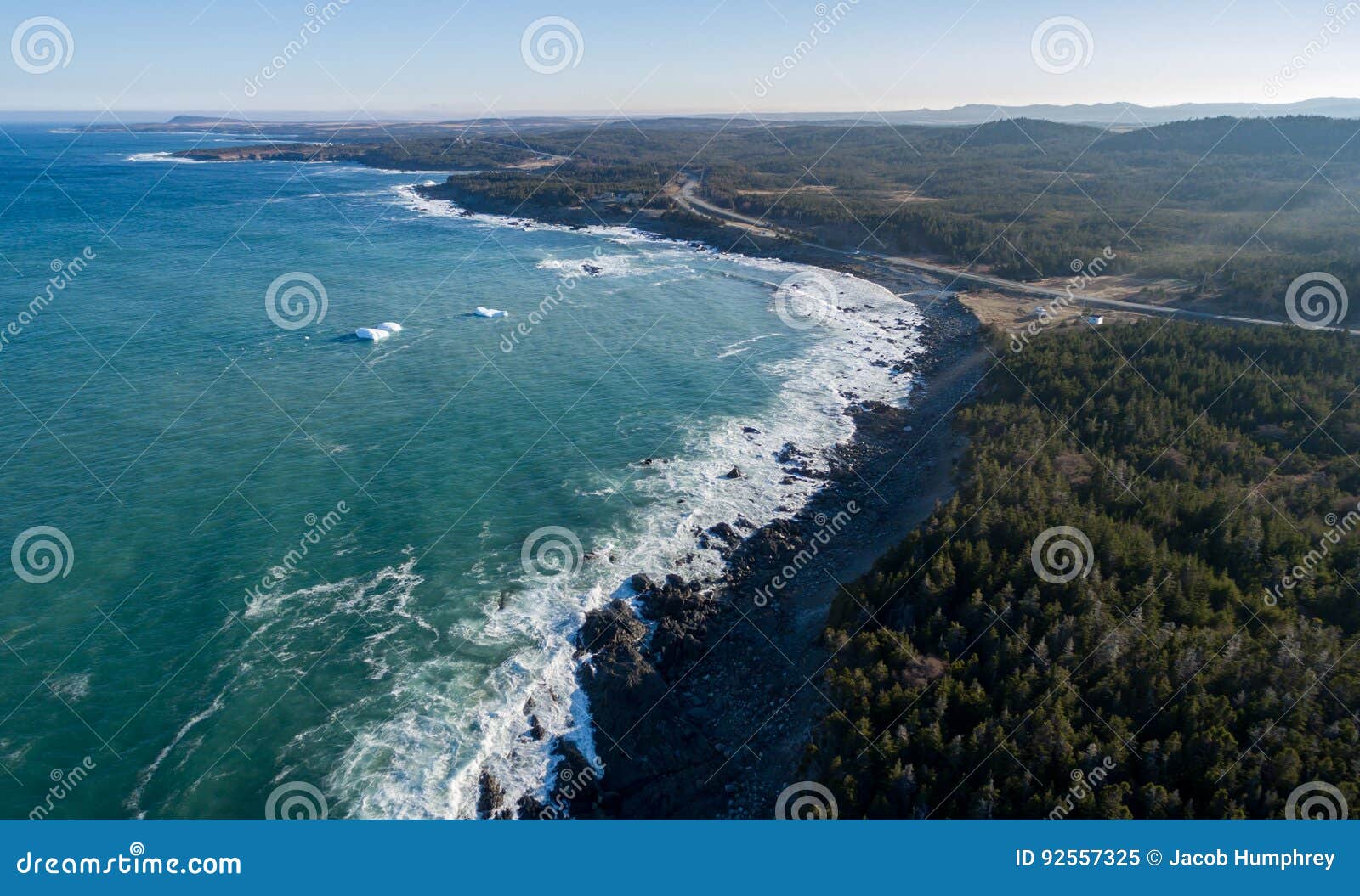 aerial image of waves crashing oiver icebergs and the newfoundland coast