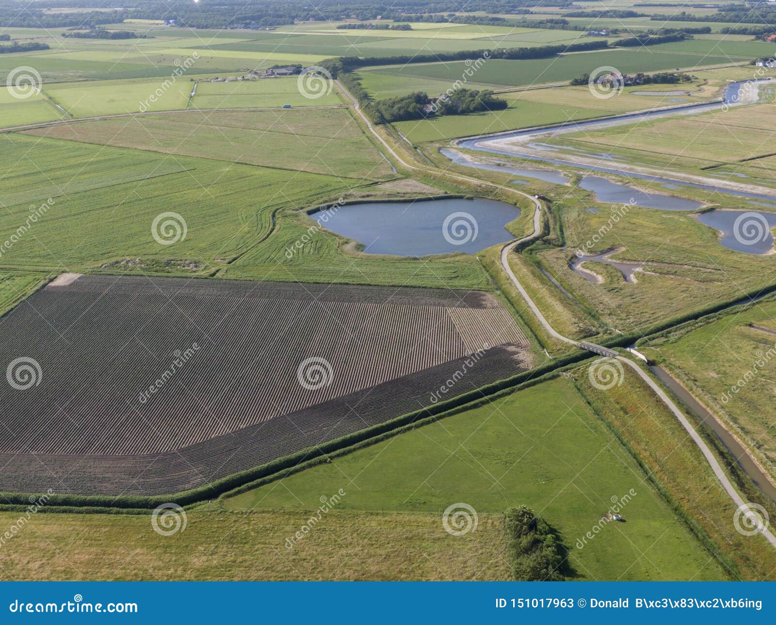 aerial of meadowland with curving dike cycle lane and water storage on the dutch island of texel