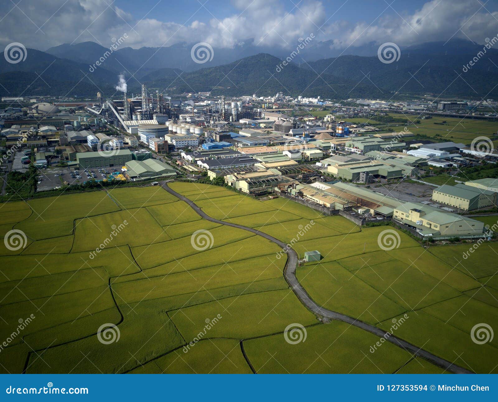 aerial panoramic view of a factory with smoking chimneys by green rice paddies in yilan ilan