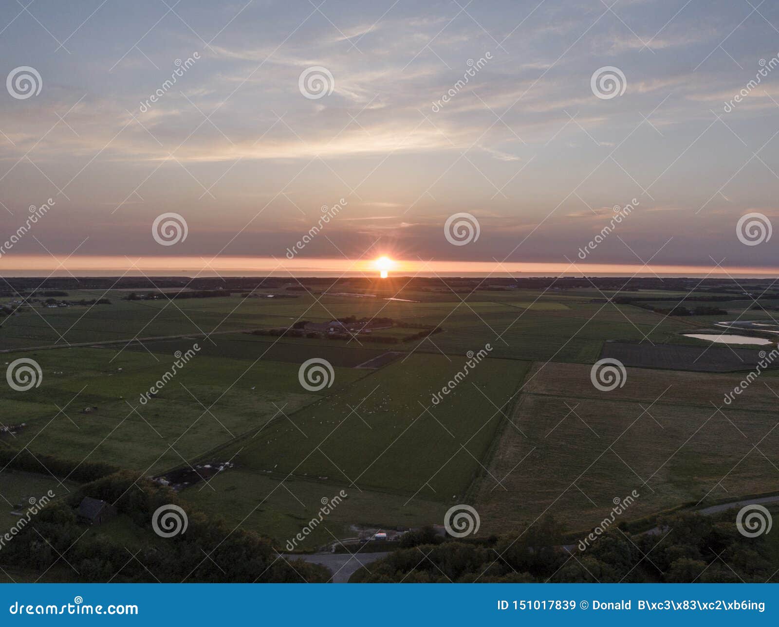 aerial of sunset over agricultural meadowland and sea on the dutch island of texel