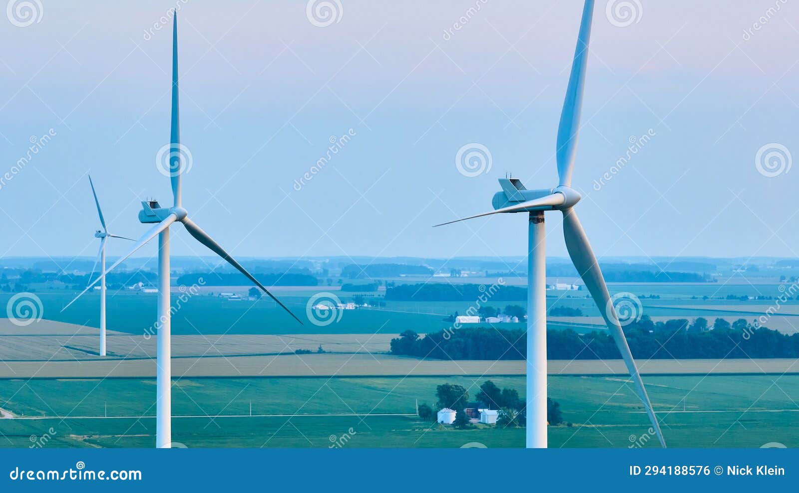 aerial three wind turbines on farmland during hazy sunset