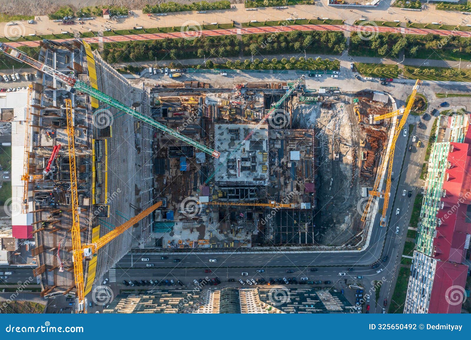 aerial top view of large construction site with multiple cranes and building structures in urban area, progress of