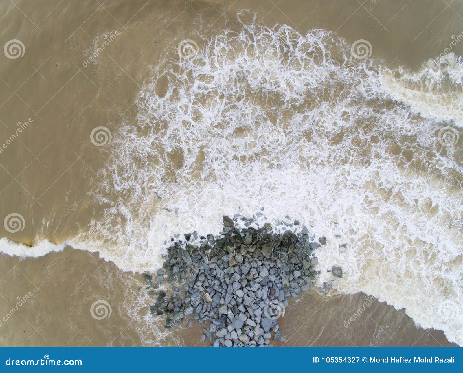 aerial top view of sea waves hitting rocks on the beach in pantai cahaya bulan