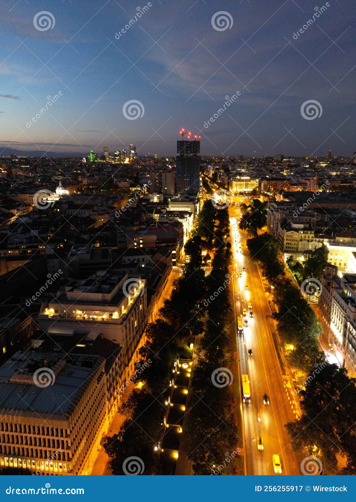 aerial vertical view of the illuminated streets of an urban cityscape under the blue sunset sky