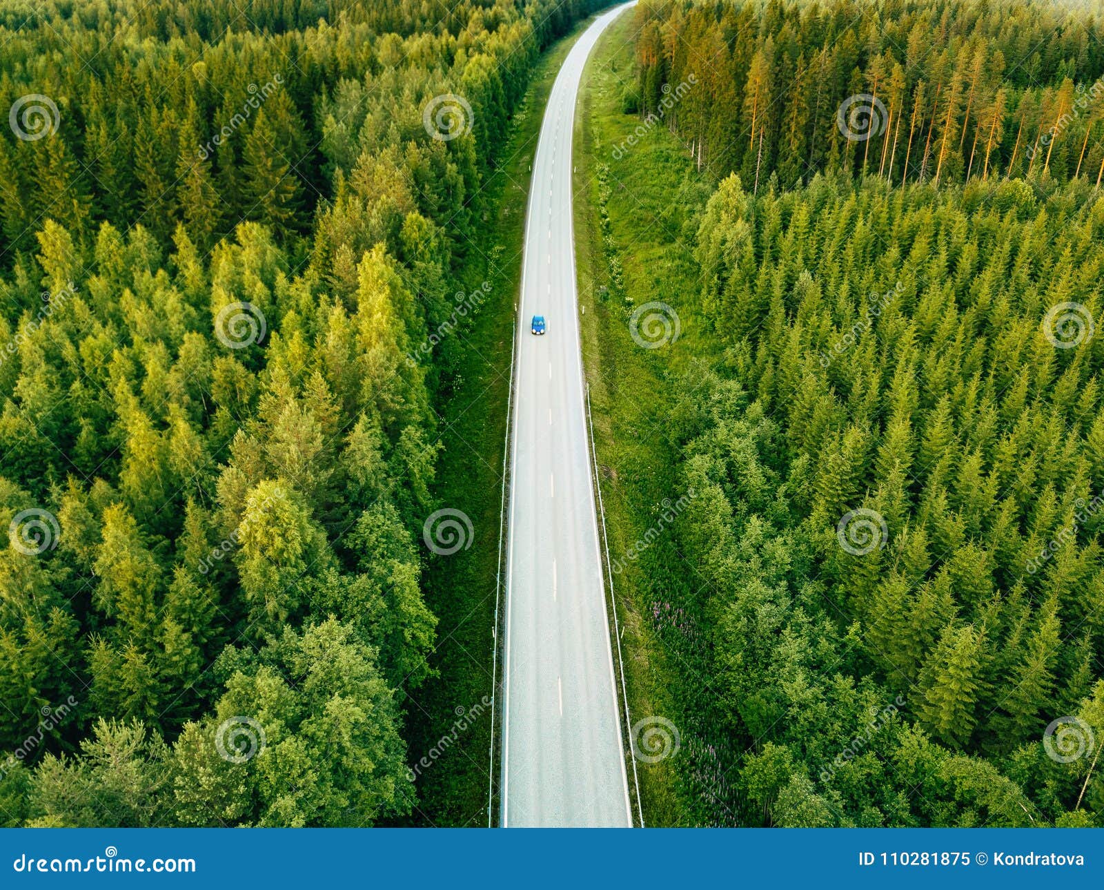 aerial view from above of country road through the green summer forest in summer finland.