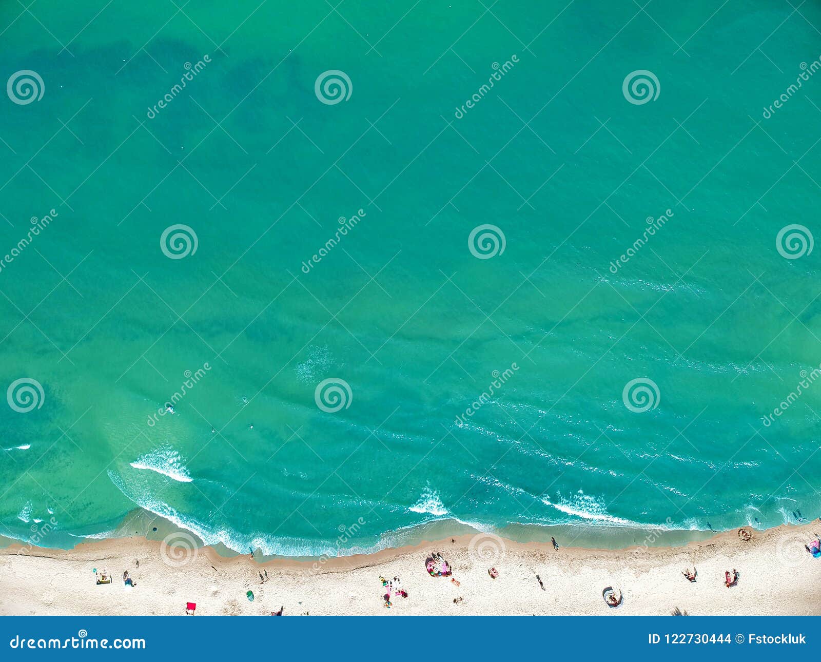 aerial view on a clean sand beach and blue ocean with sunbathers