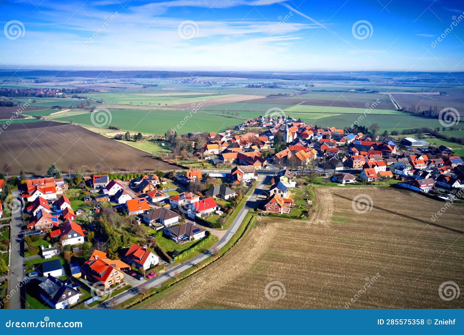 aerial view from the edge of a small german village beetween fields and meadows with family houses and small gardens