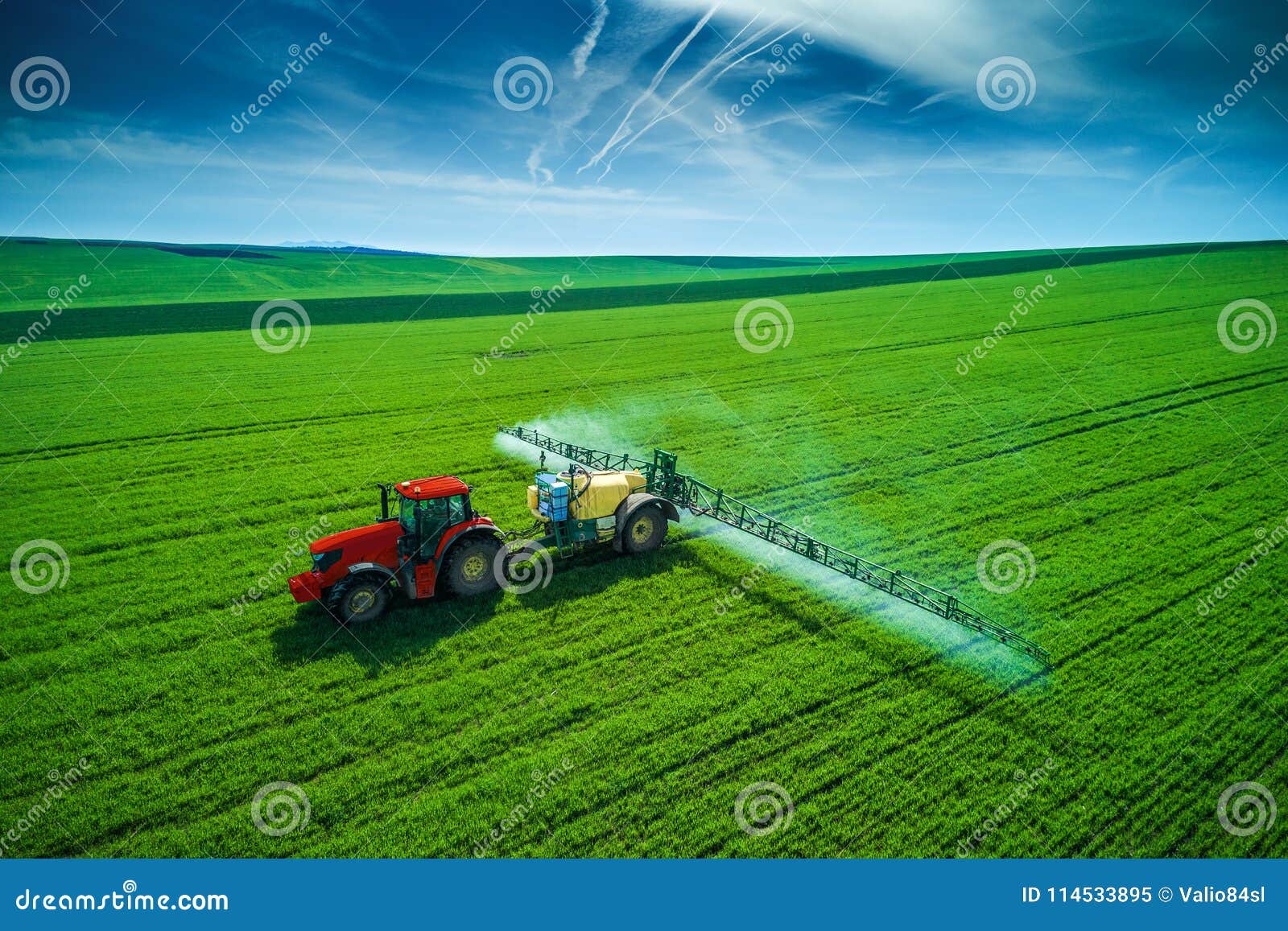 aerial view of farming tractor plowing and spraying on field