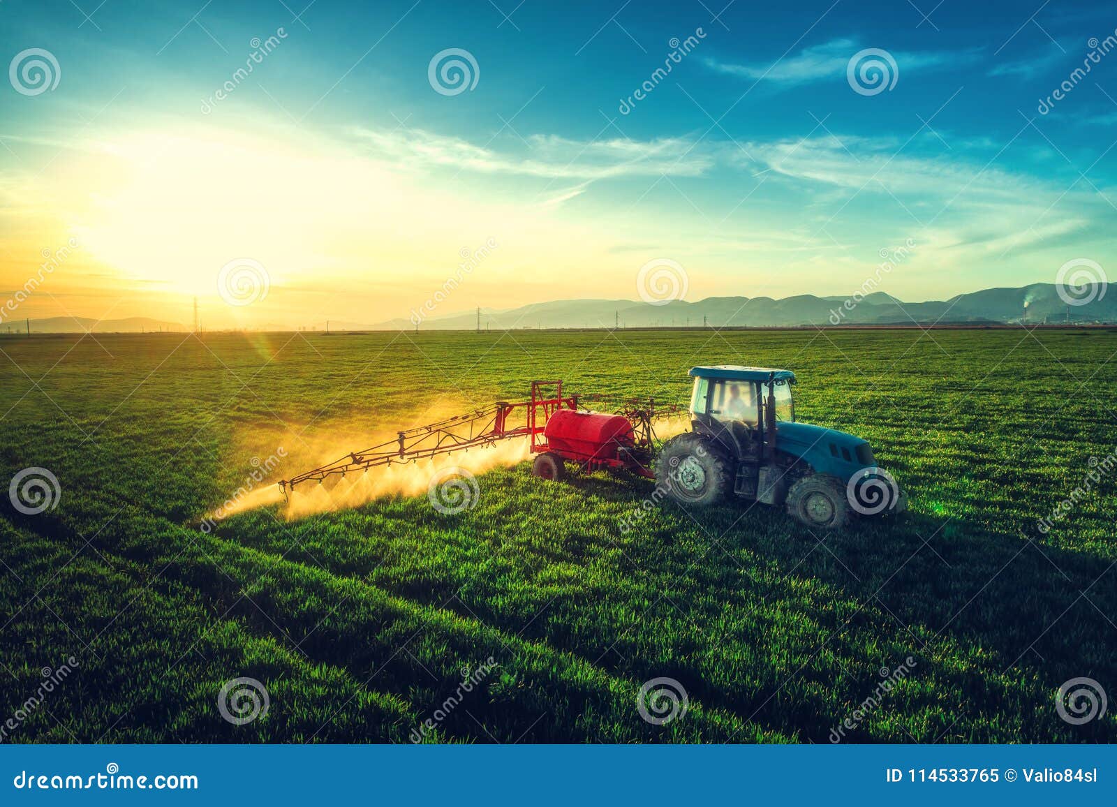 aerial view of farming tractor plowing and spraying on field